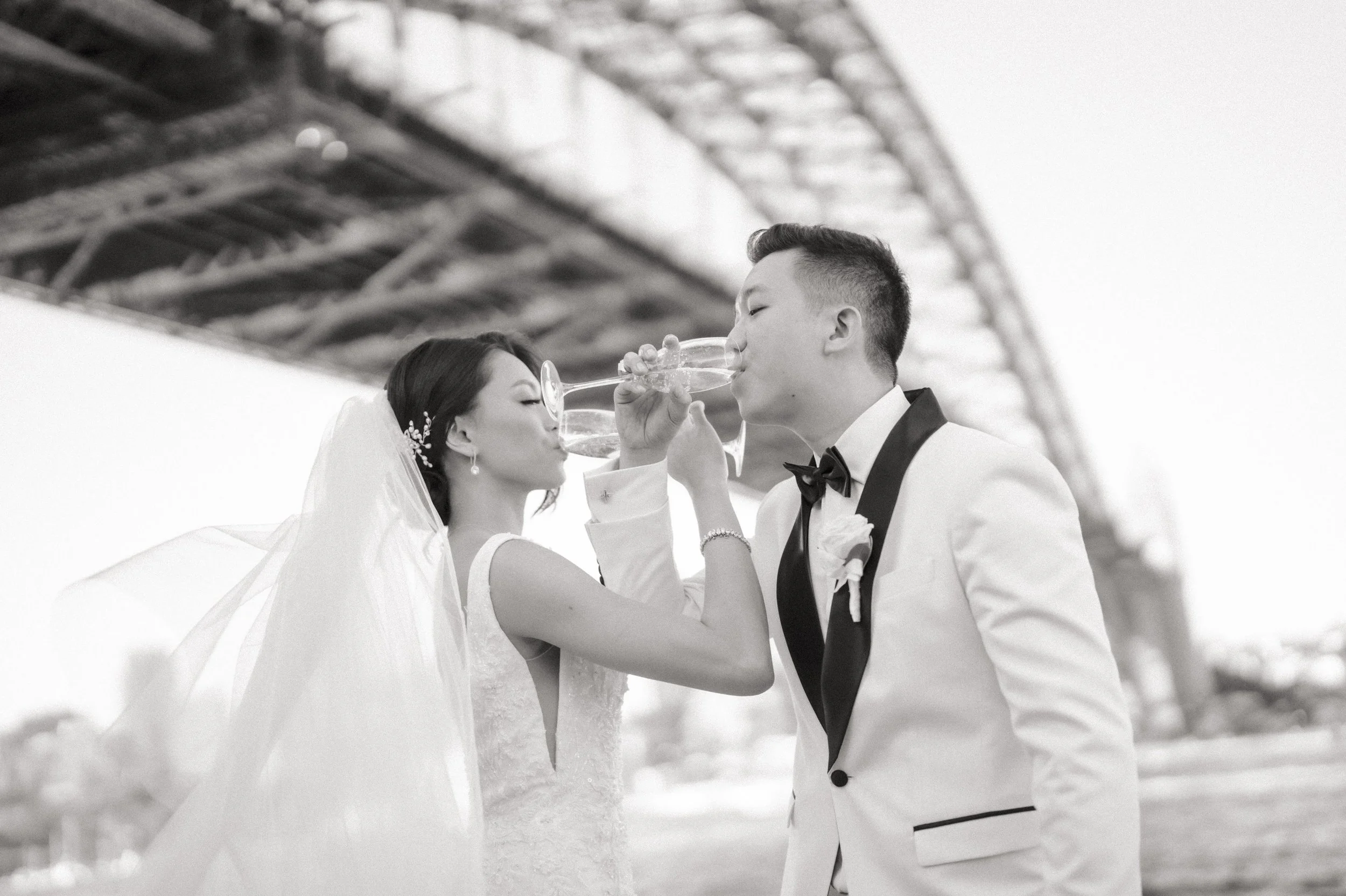 Bride and groom sharing a champagne toast under the harbour bridge
