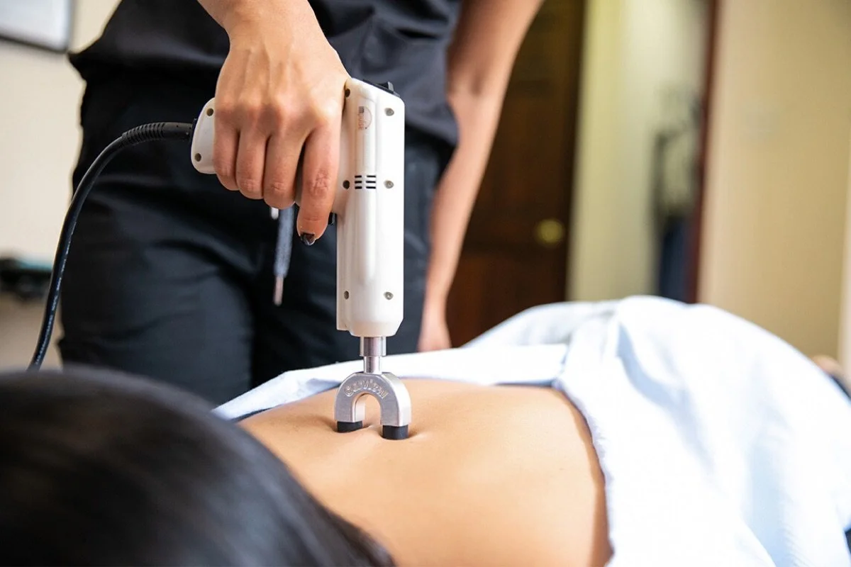 Chiropractor placing the Impulse IQ adjusting instrument on a woman's upper back