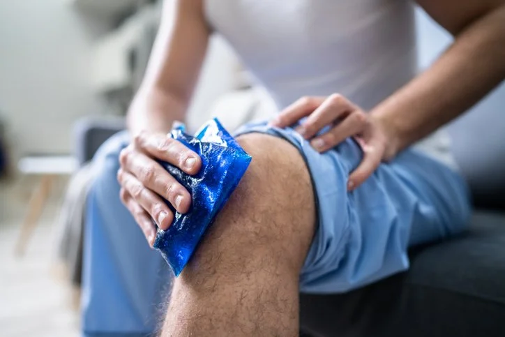 A man seated with an ice pack on his knee