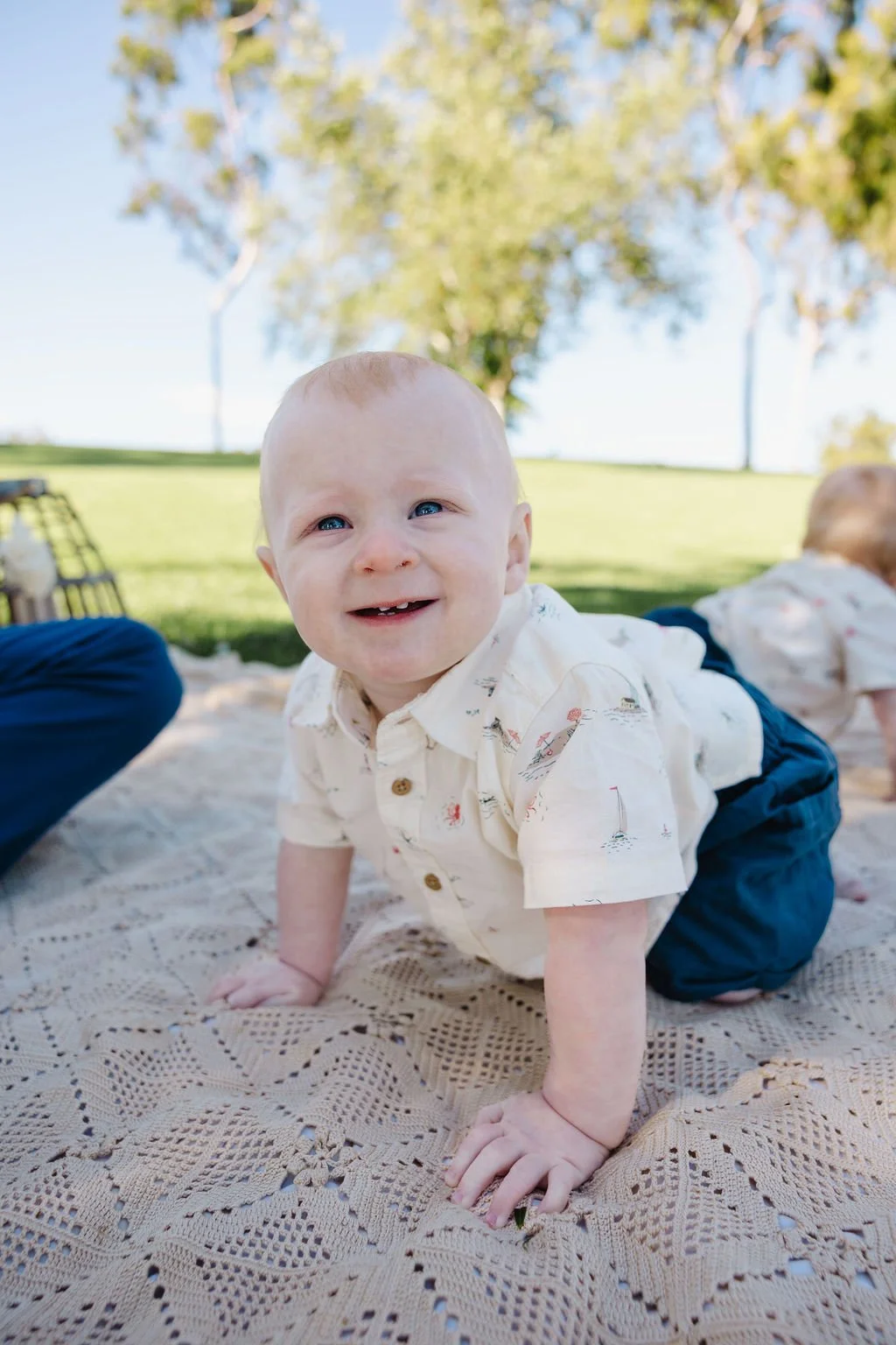 James on his hands and knees on a blanket at the park