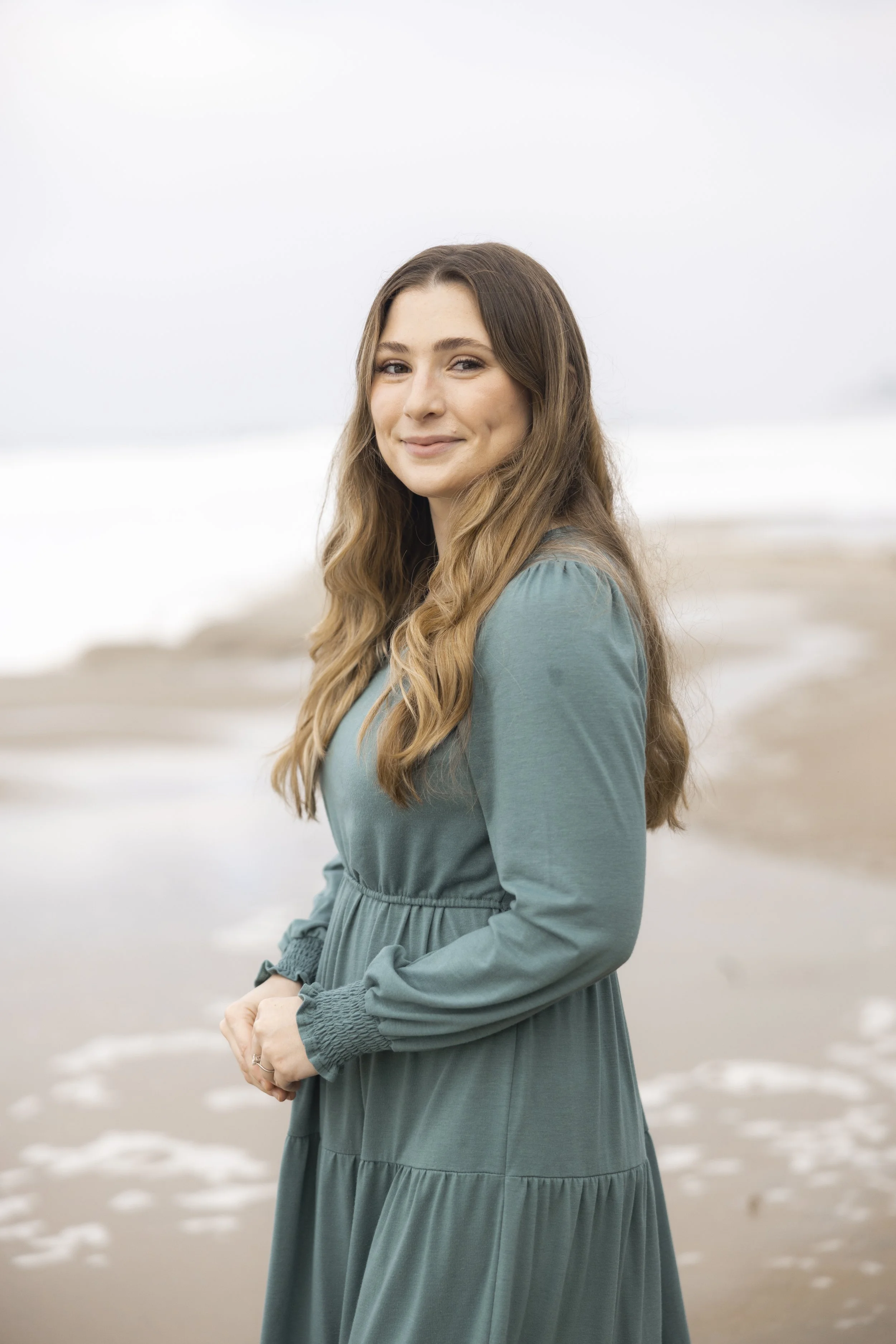 Dr. Caitlyn standing on the beach in a green dress