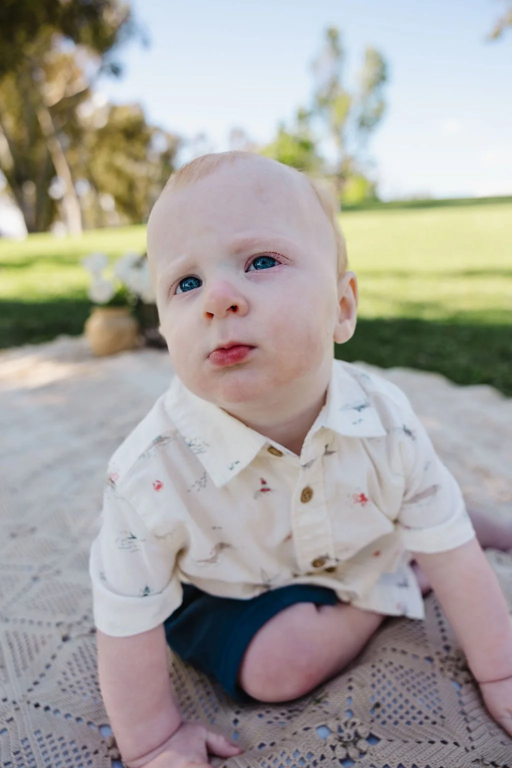 Henry sitting on a blanket at the park