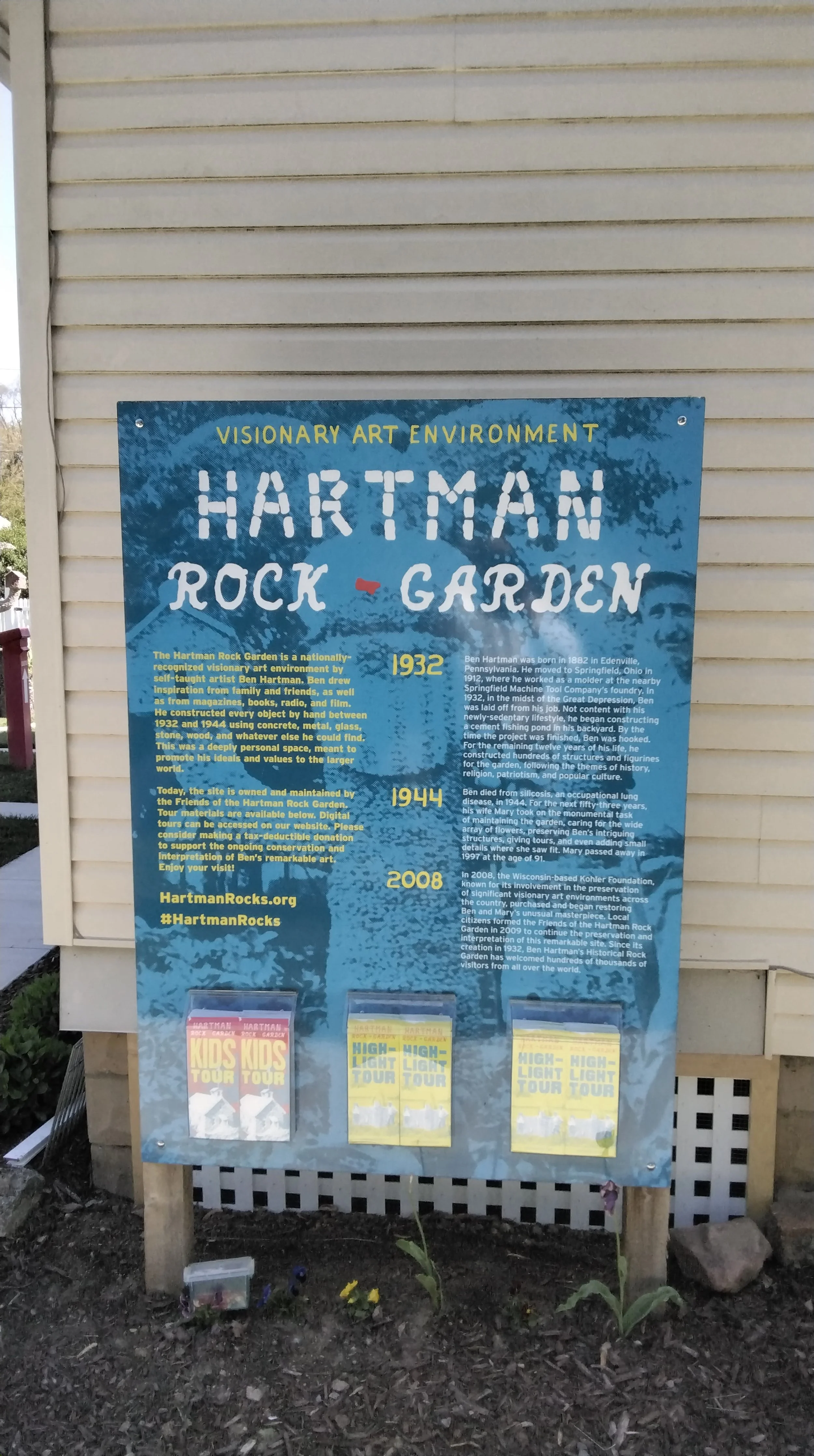 Signboard about Hartman Rock Garden with historical information and flyers for tours.