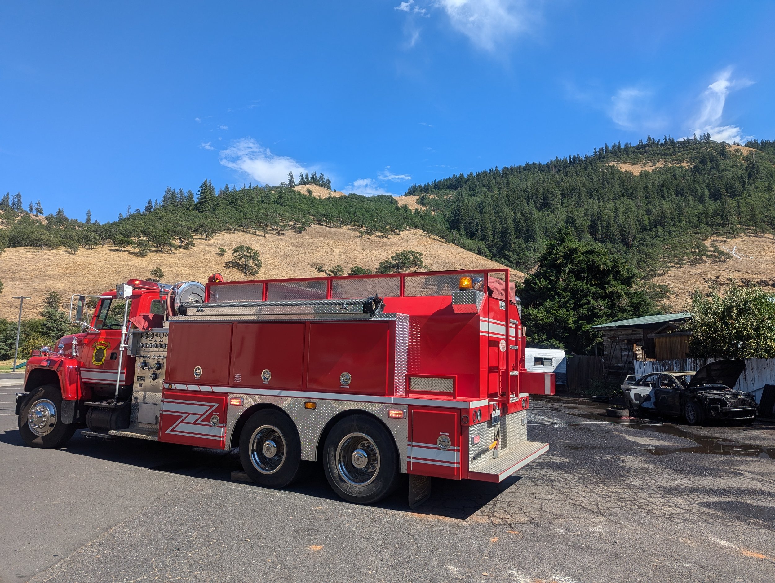 Klickitat's Attack Tender 1203 at the scene of a car fire in Klickitat. The car's proximity to the nearby fence and wooden buildings almost resulted in a catastrophic structure fire. July 16, 2024