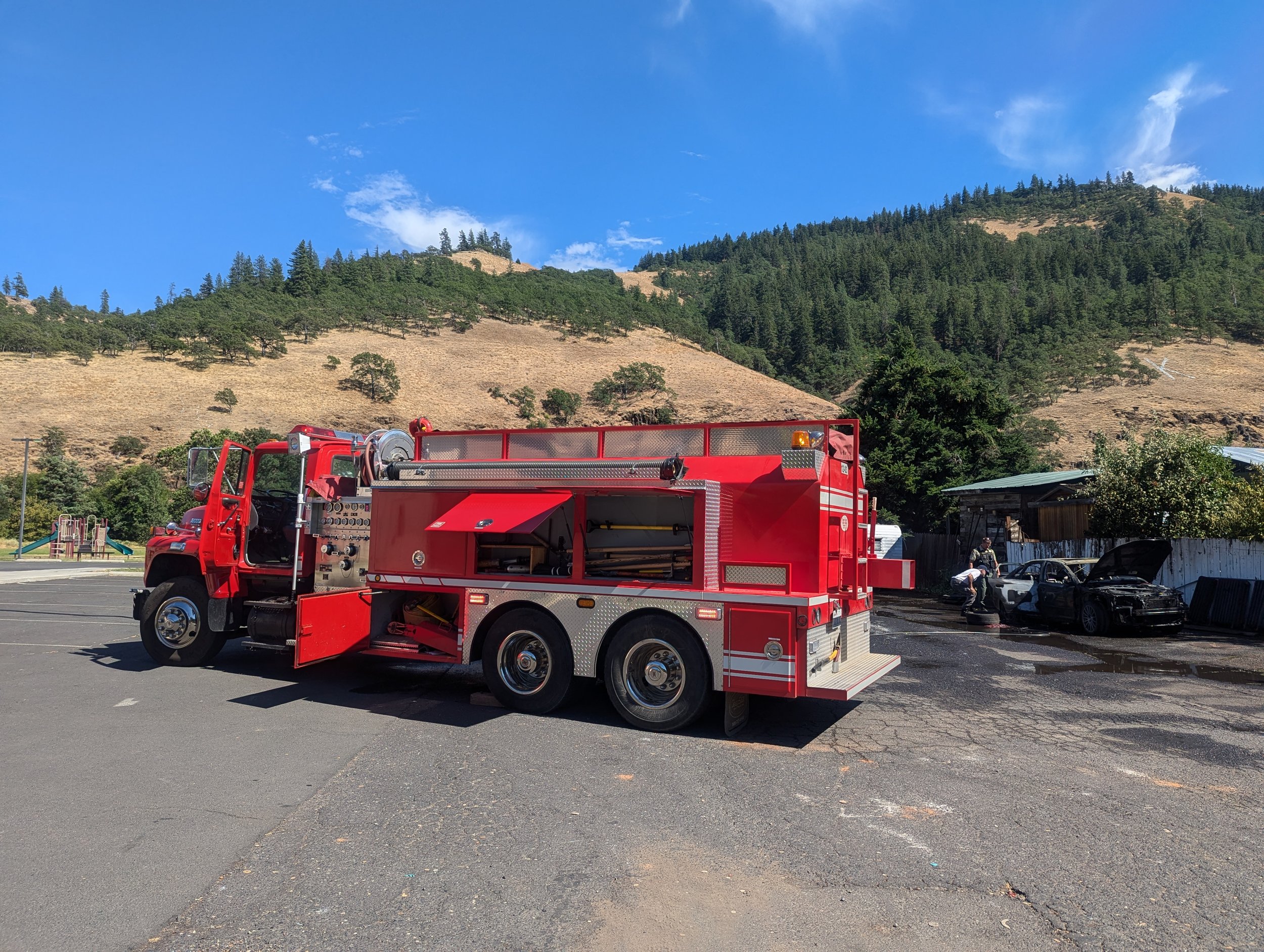 Klickitat's Attack Tender 1203 at the scene of a car fire in Klickitat. The car's proximity to the nearby fence and wooden buildings almost resulted in a catastrophic structure fire. July 16, 2024