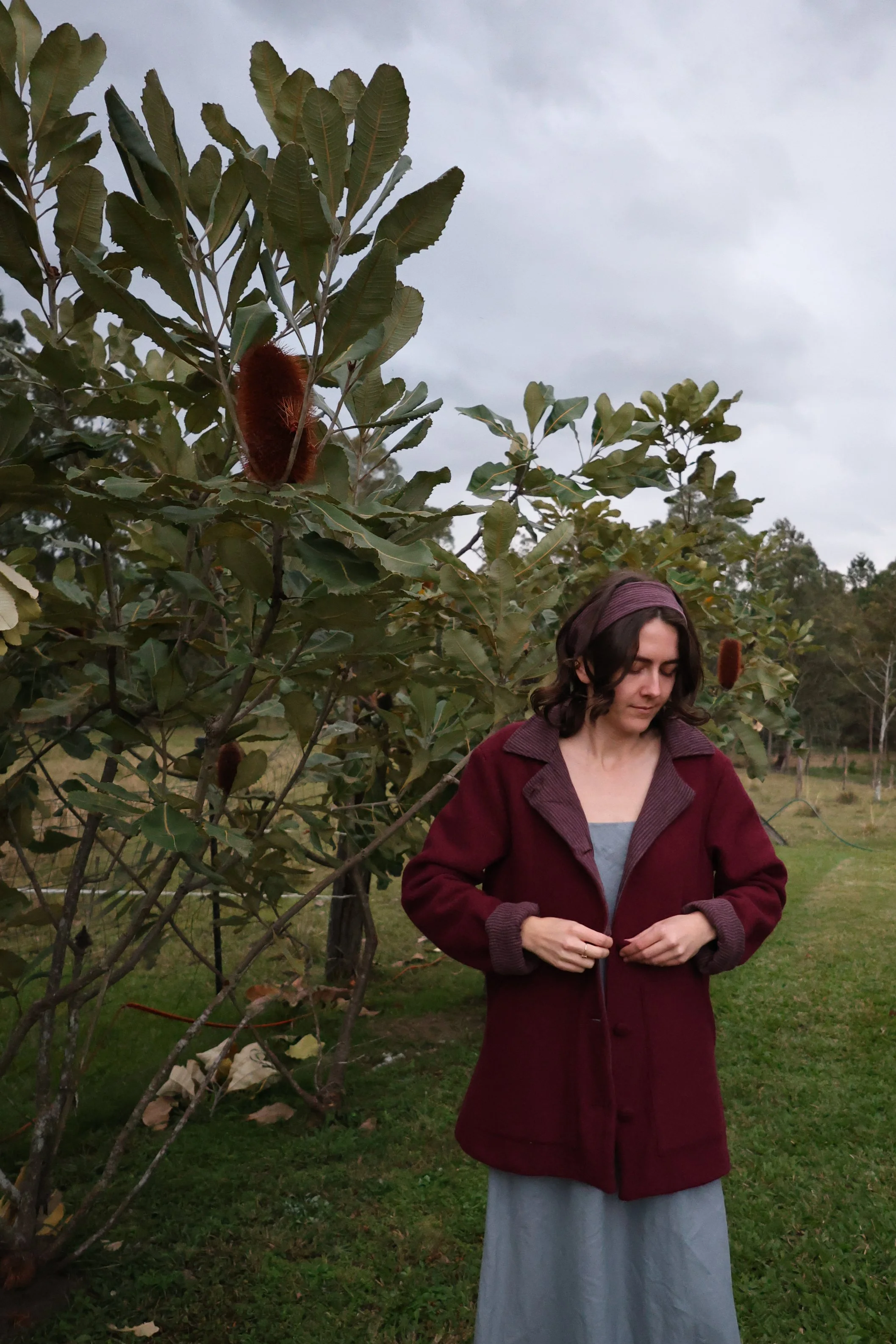A woman in a wool coat in a deep currant colour. pops of contrast lining are featured in the colour cuffs and centre front.