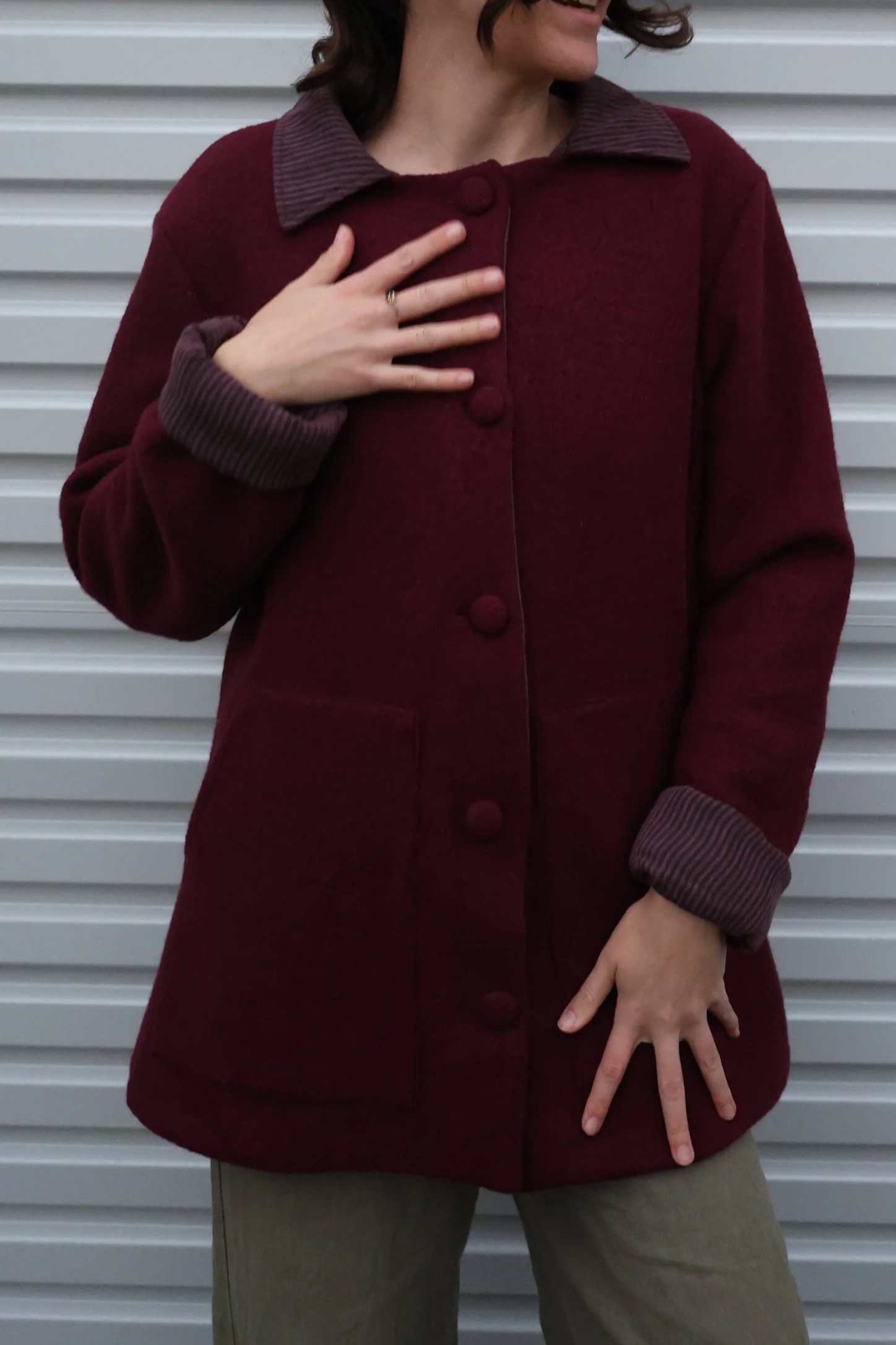 A closeup of a wool coat with contrast cuffs and collar. Buttoned up with matching wool covered buttons.