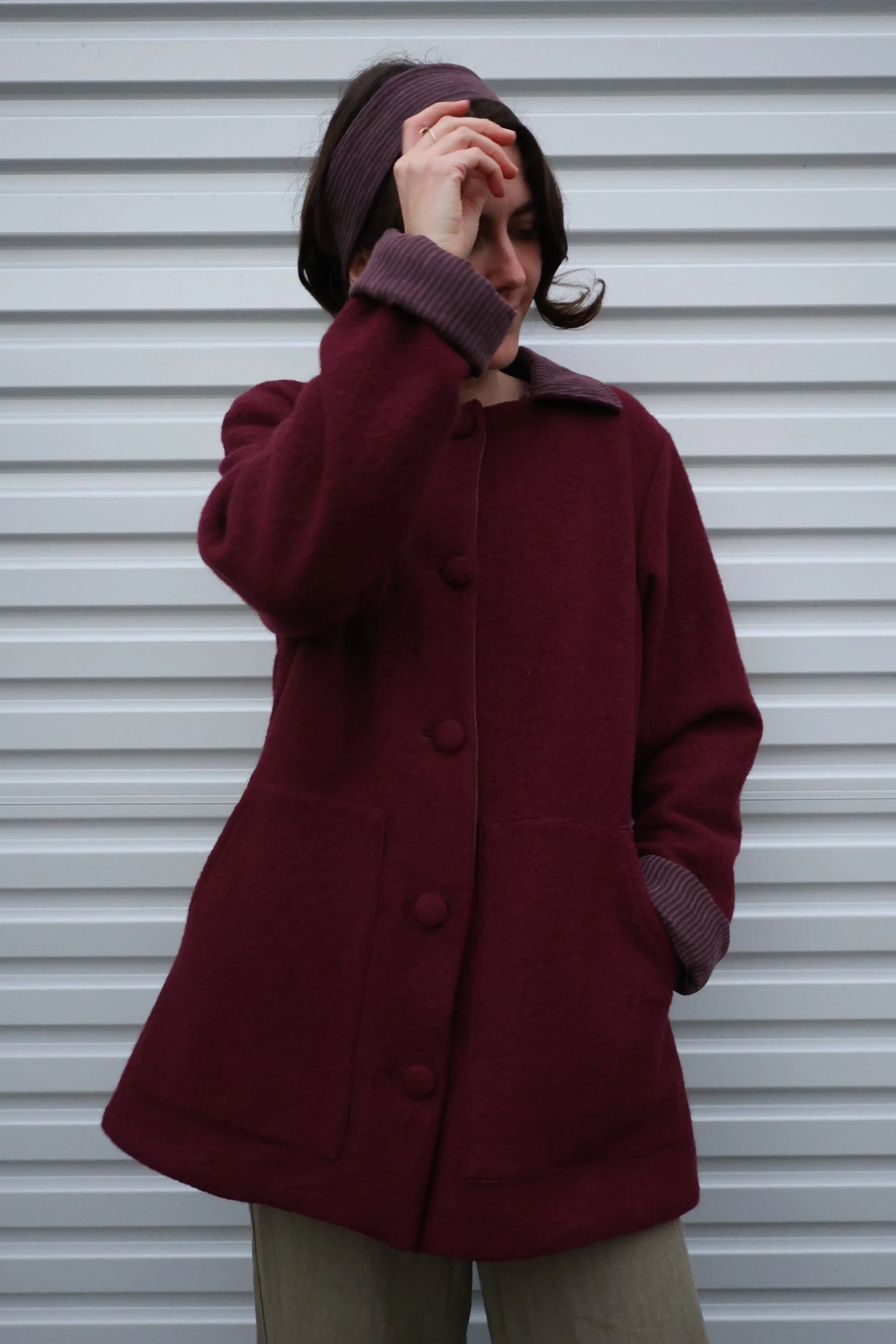 A cute and comfortable wool coat in a reddish tone. It features pops of contrast linen, cotton lining in a stripe pattern.