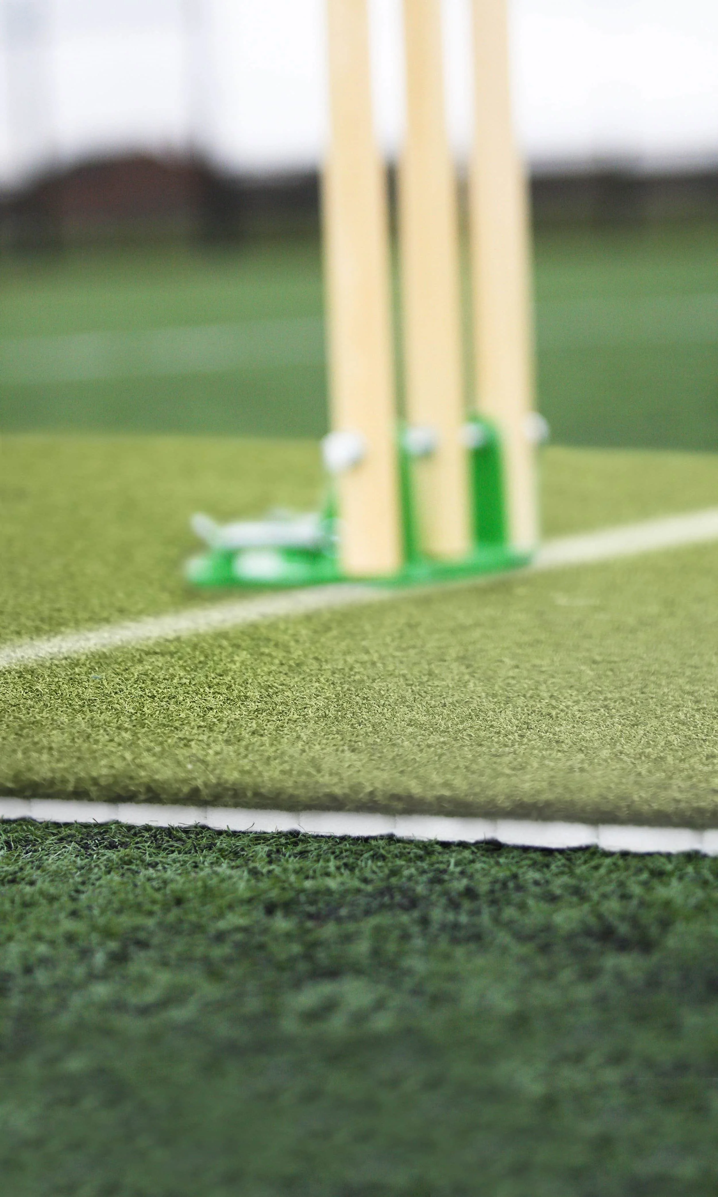 Cricket stumps and bails set up on an indoor cricket pitch.