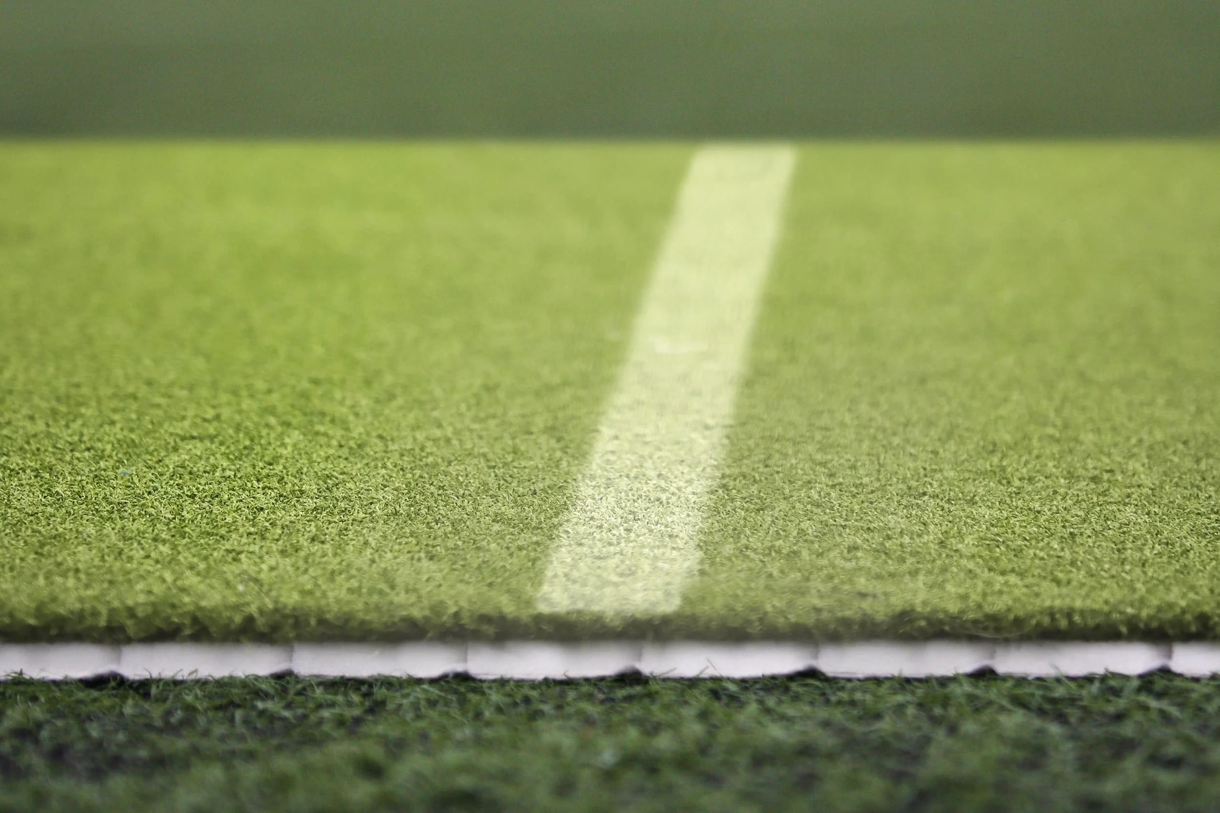 Close-up of a painted white line on a green artificial turf soccer field.