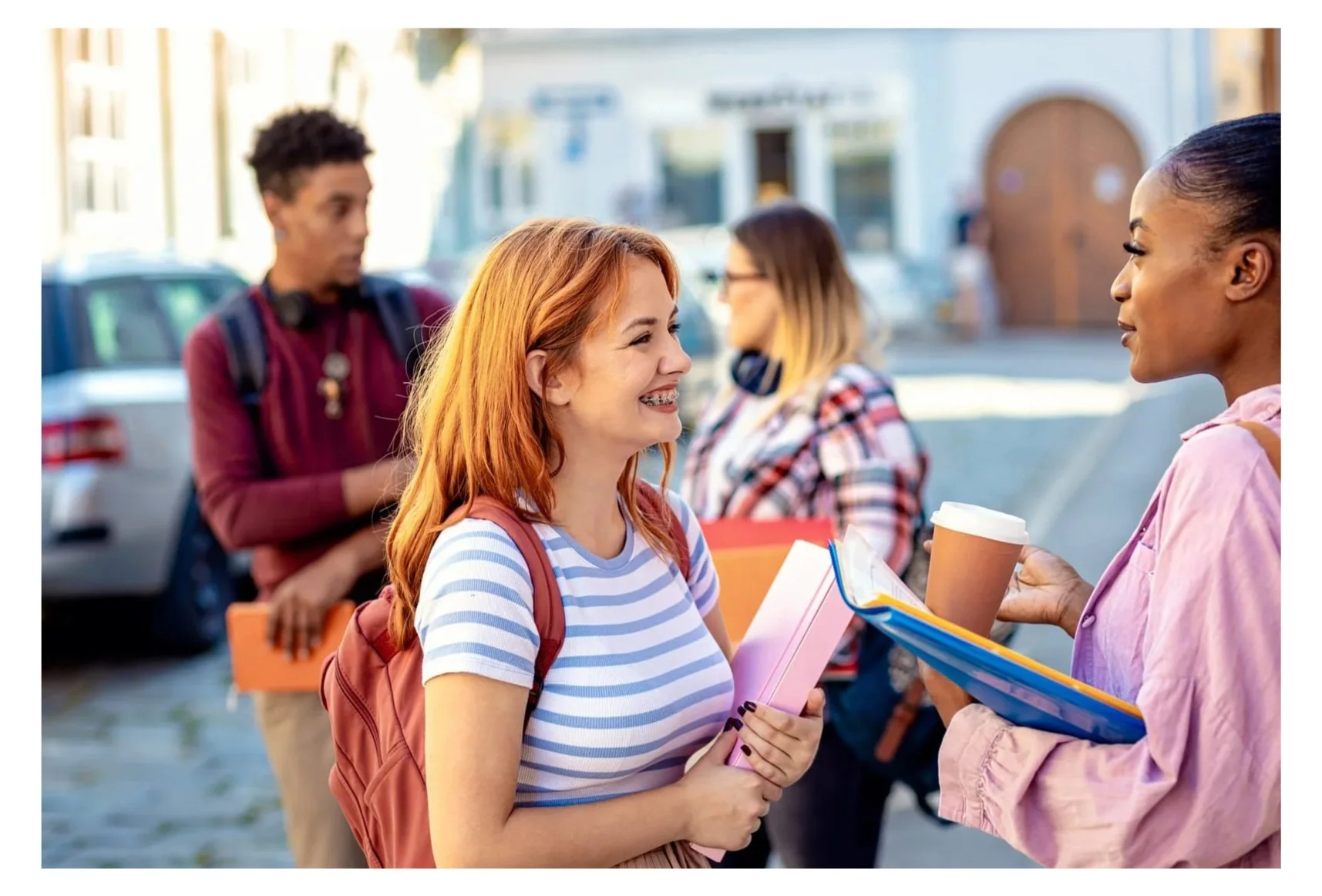 Students with backpacks and school materials talking on campus, representing the social and emotional transition from high school to college.
