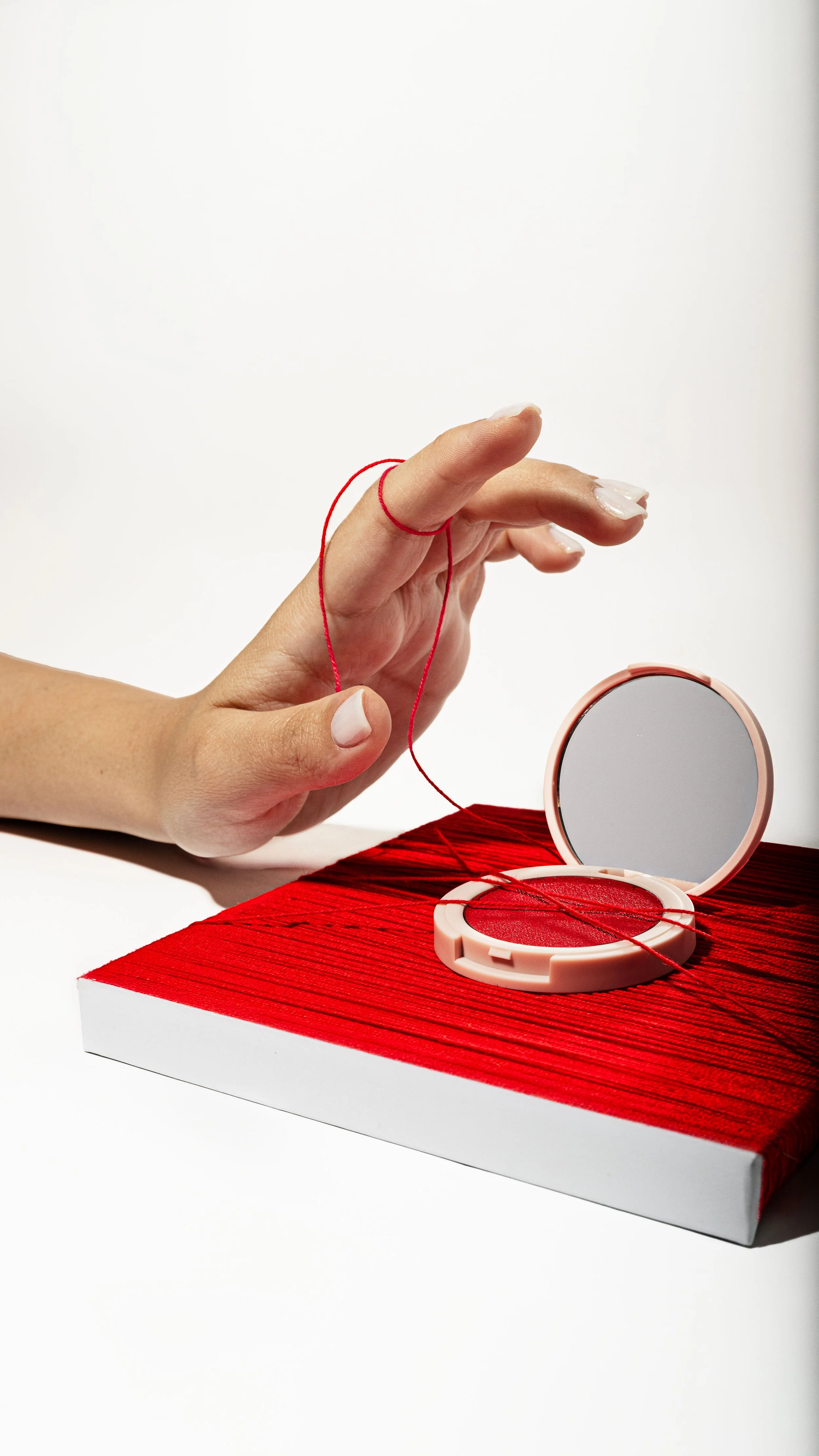 Person holding a red thread near a Kylie Cosmetics blush, with a red box in the background.