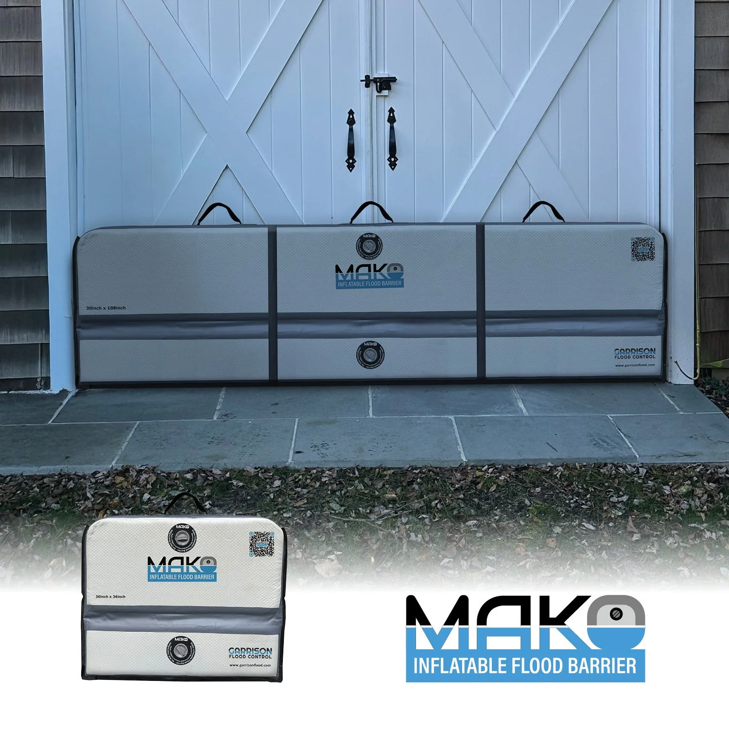 An inflatable flood barrier with the label 'MAKE Inflatable Flood Barrier,' placed in front of a white barn door with black handles. The barrier is gray and measures 30 inches by 108 inches.