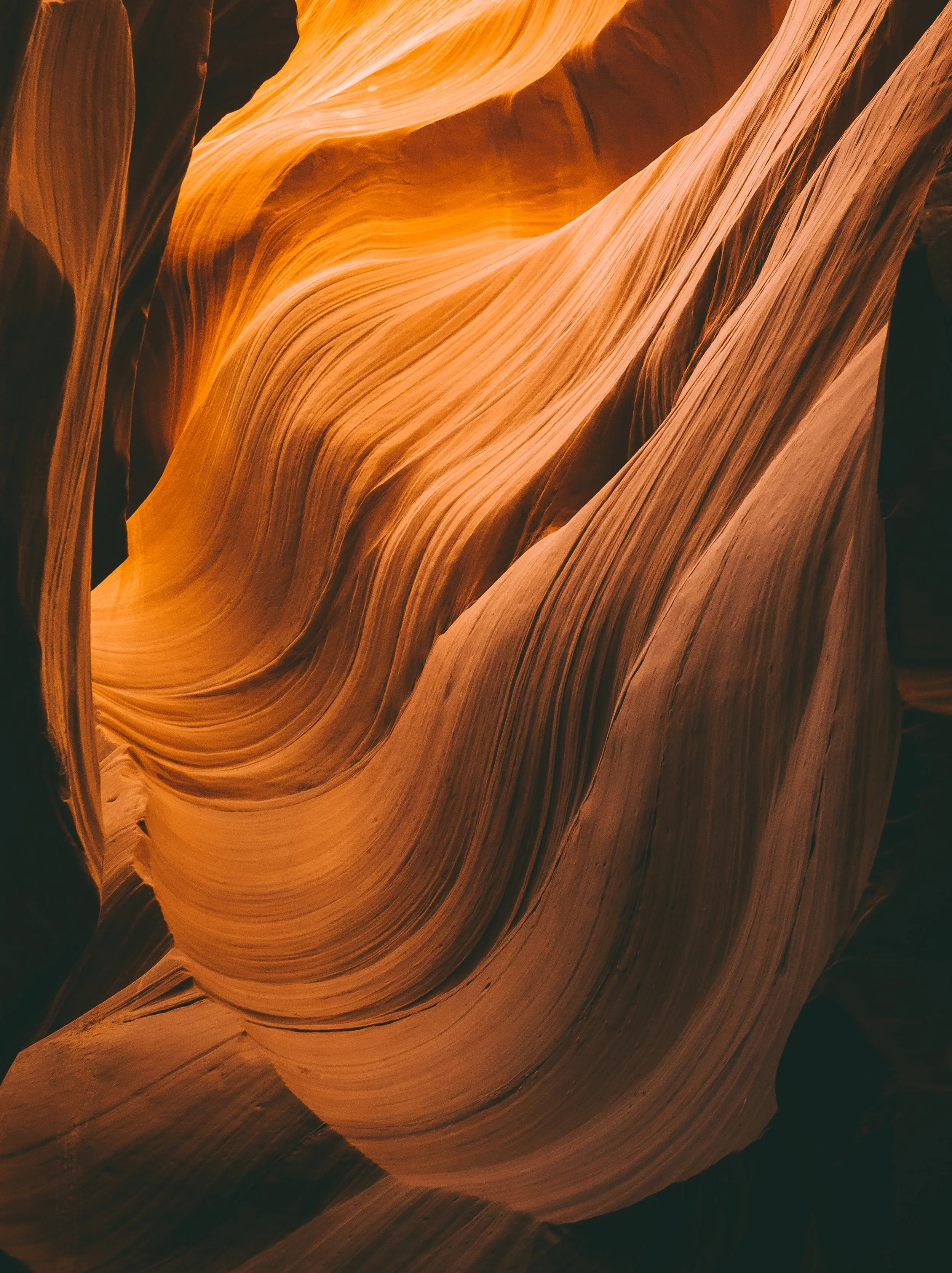 Smooth, flowing sandstone canyon walls with warm orange and tan hues, showcasing natural curves and textured formations.