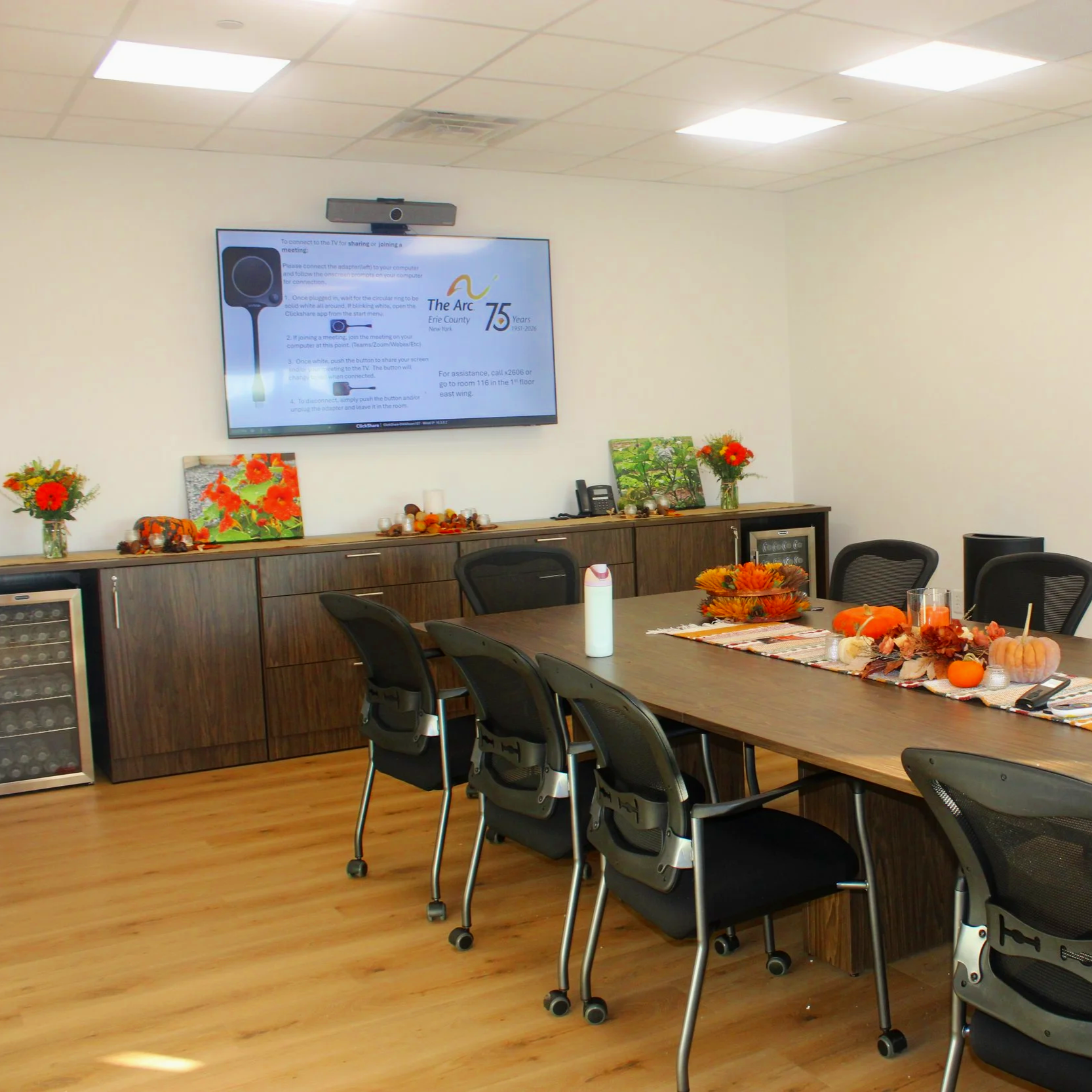 Conference Room with large table, chairs, a TV for presentations and Video conferences, fridges, and decorated in fall theme