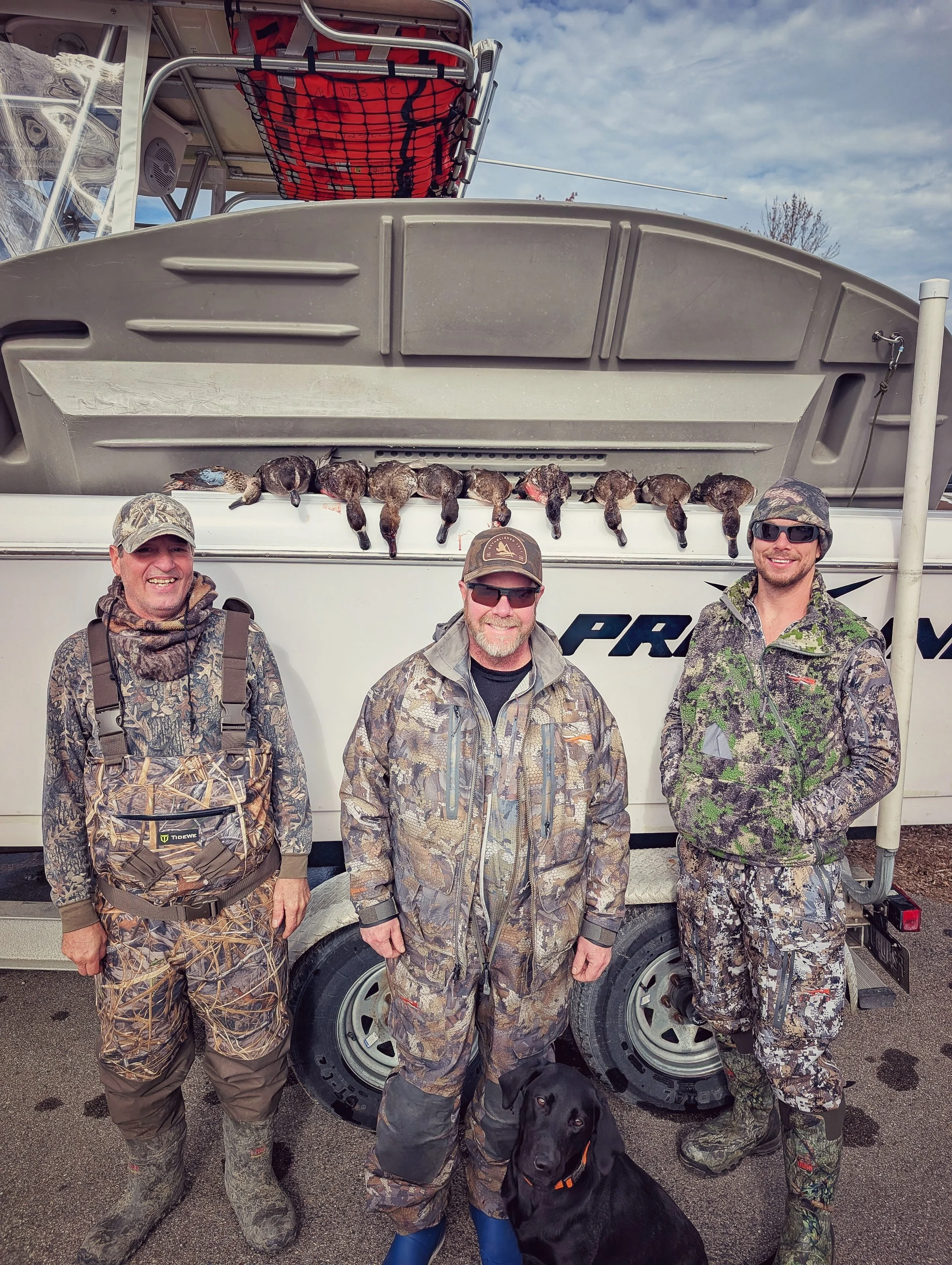 A group of waterfowlers and their retriever posing with a limit of Lake Huron Blue Bills in front of the Proline tender boat.