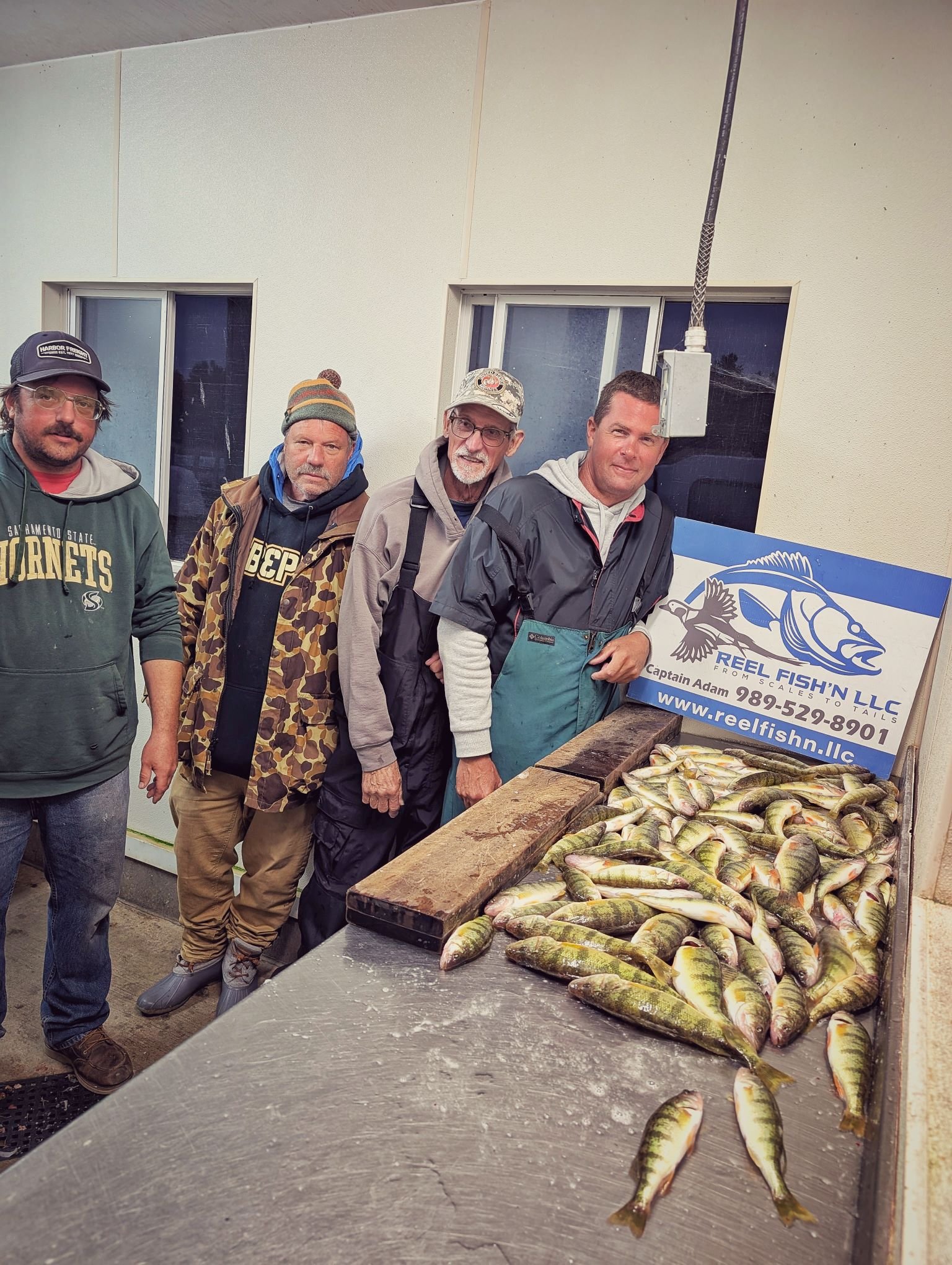 A large group of anglers standing behind a full limit of fall perch caught during a September charter on Drummond Island with Reel Fish'n.