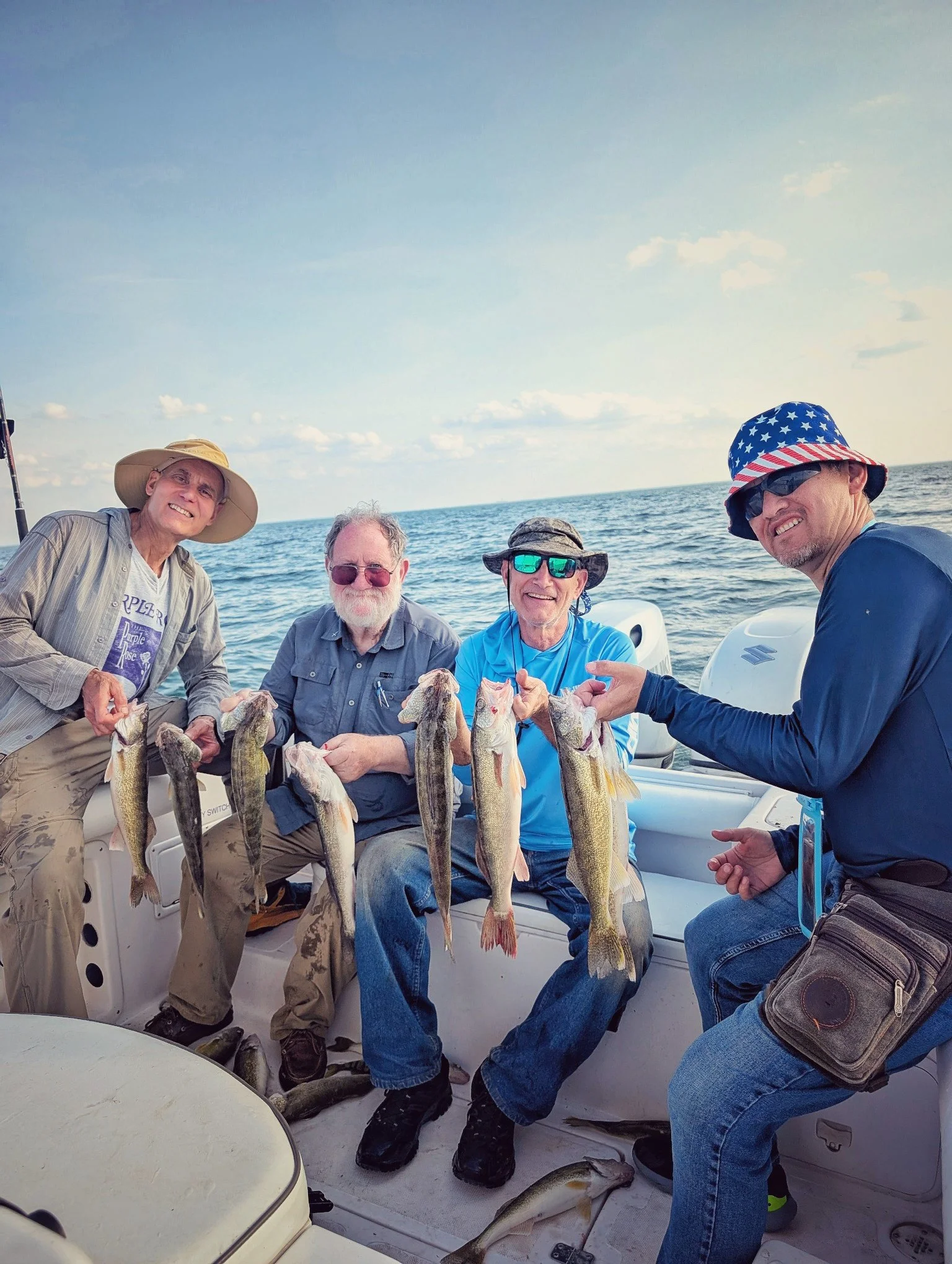  A group of friends showcasing their fresh-caught walleye on the deck of a Reel Fish'n LLC charter boat during a summer morning fishing trip on Saginaw Bay. 