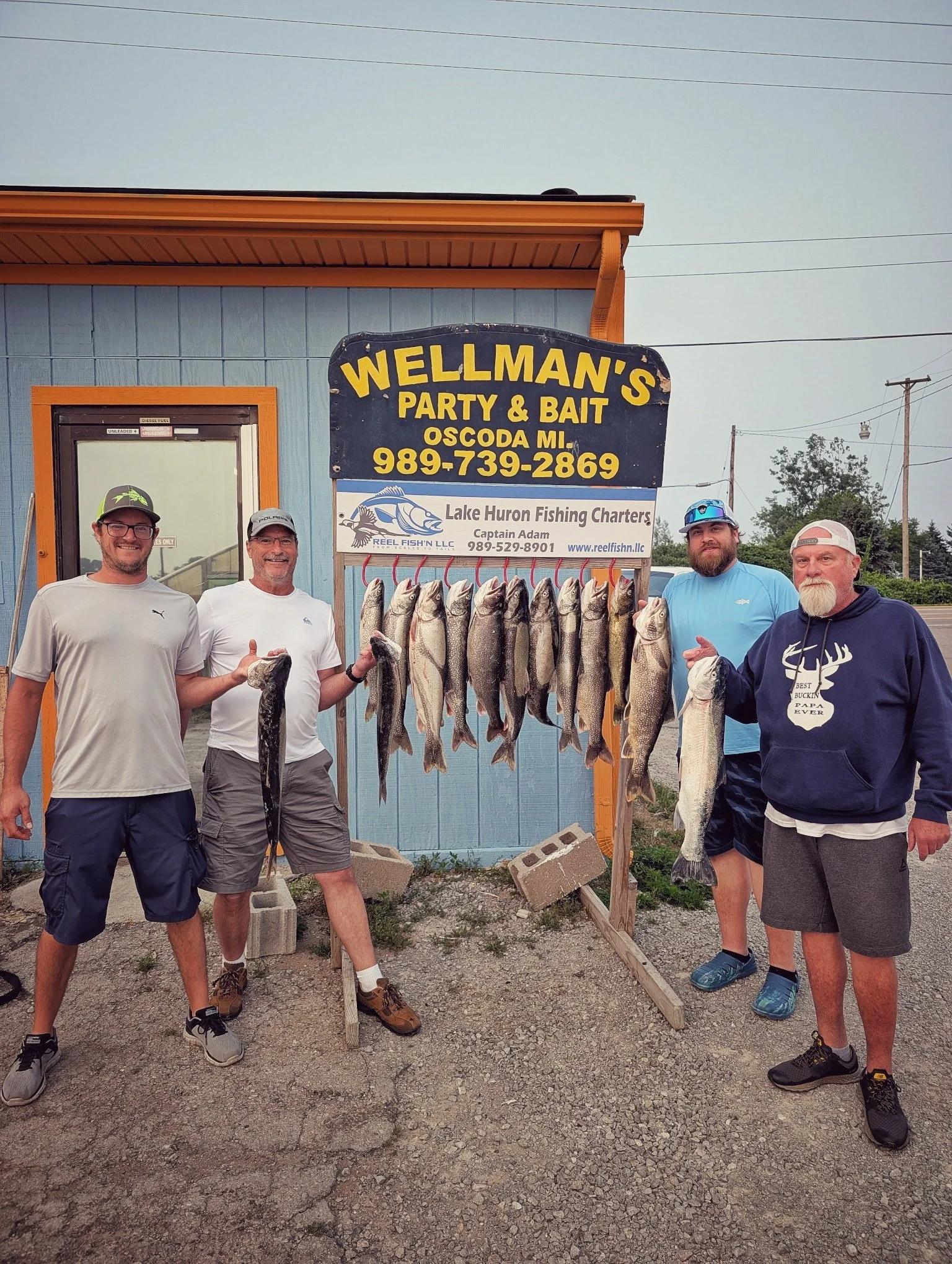 A successful group of anglers displaying a full limit of Lake Huron Salmon and Trout at the iconic Wellman's Party &amp; Bait in Oscoda after a Reel Fish'n charter. 