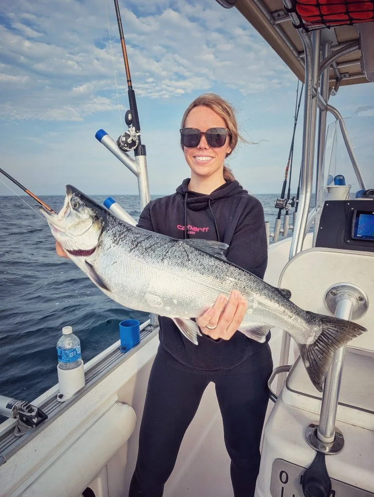  A female angler showcasing a silver Coho Salmon caught on Lake Huron while fishing out of Oscoda, Michigan, with Reel Fish'n LLC. 