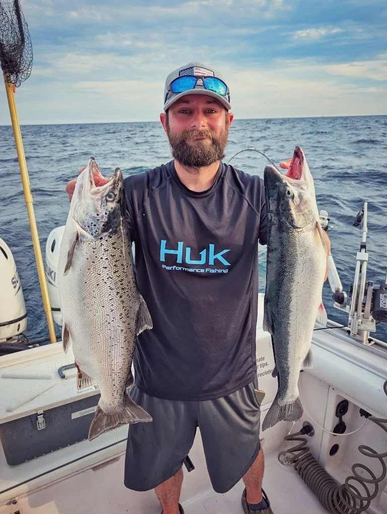  A fisherman in Huk gear displaying two large Lake Huron salmon caught on a professional Reel Fish'n LLC charter boat out of Oscoda, MI. 