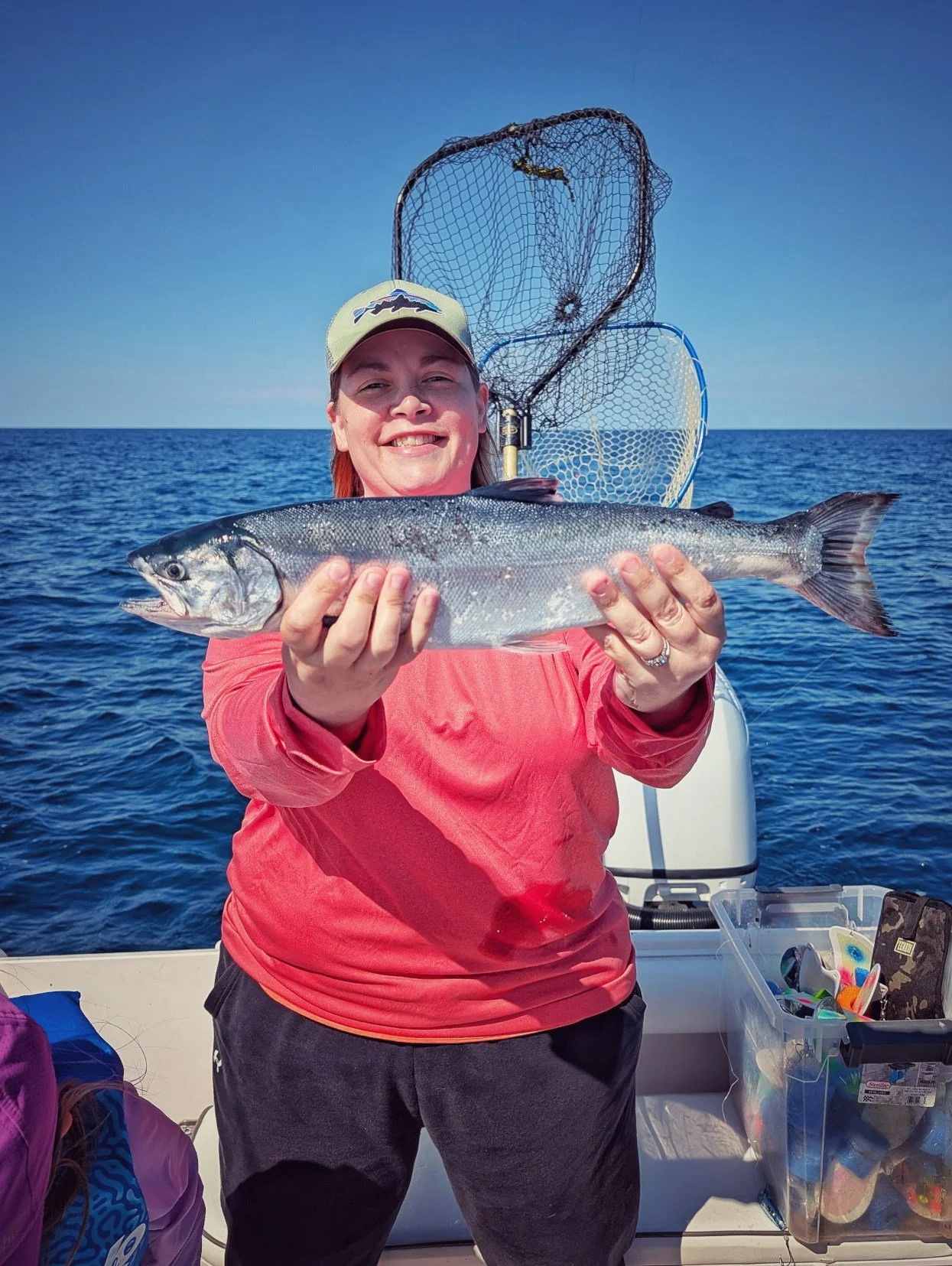  A female angler holding a silver Atlantic Salmon caught on a sunny summer day while offshore fishing in Oscoda with Reel Fish'n on Lake Huron. 
