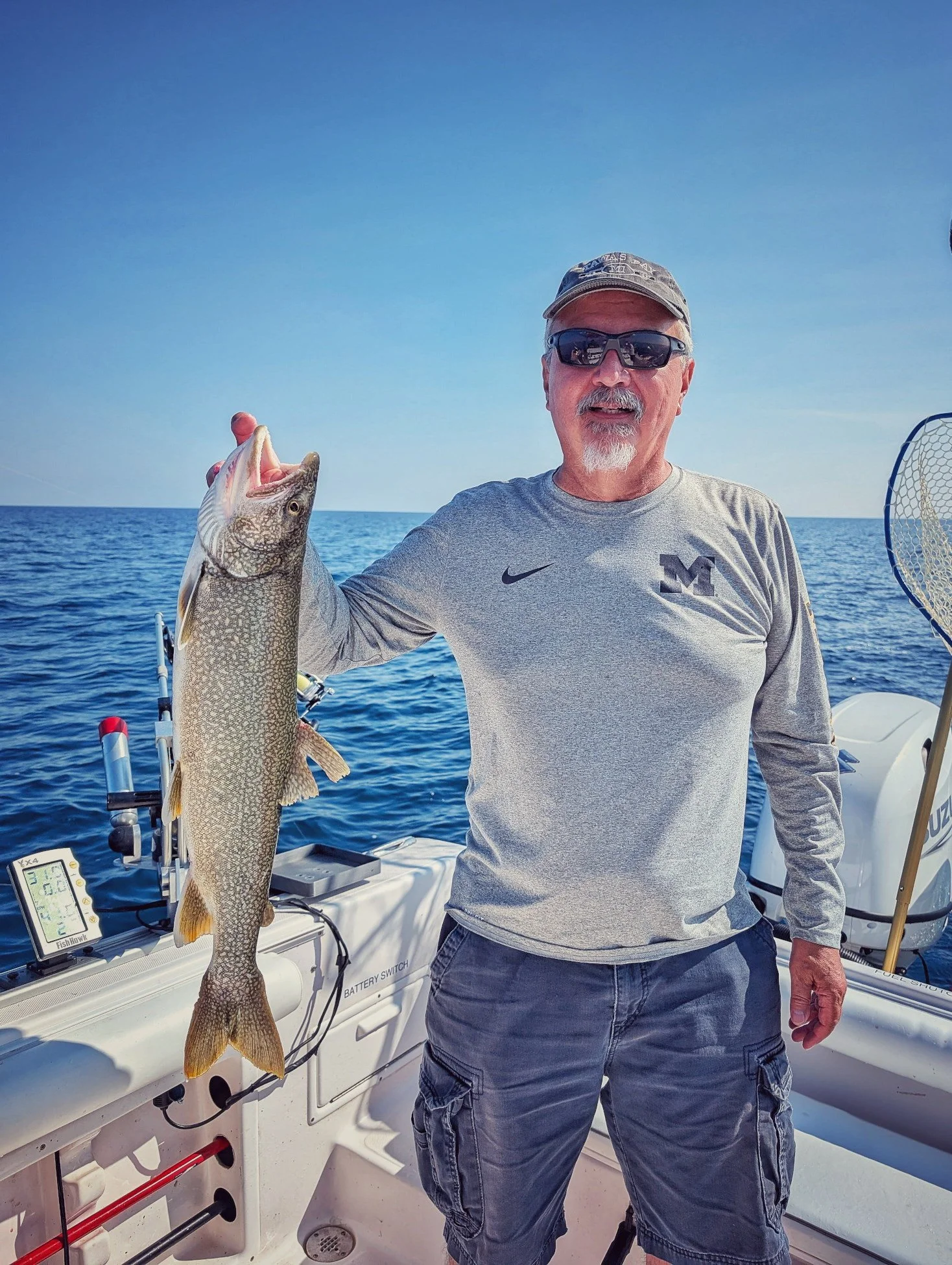  A male angler holding a fresh-caught Lake Trout on the deck of a Reel Fish'n charter boat during a summer fishing trip on Lake Huron in Oscoda. 