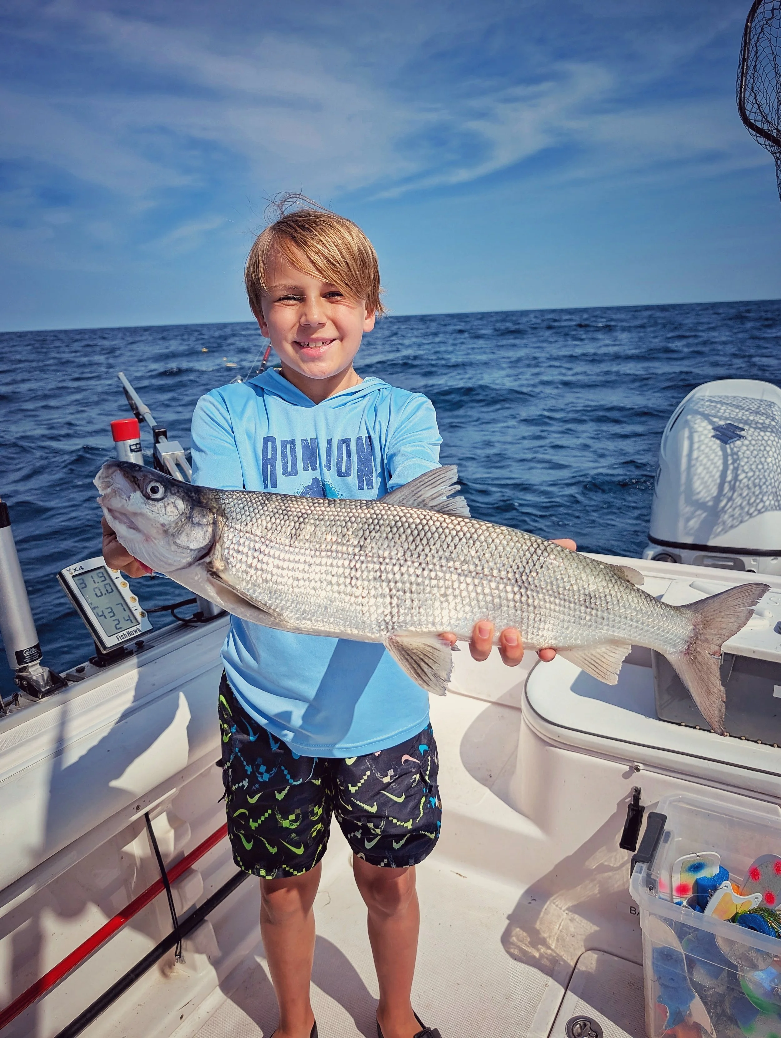  A young boy proudly displaying a fresh-caught whitefish during a family fishing adventure in Oscoda, Michigan, with Reel Fish'n LLC. 