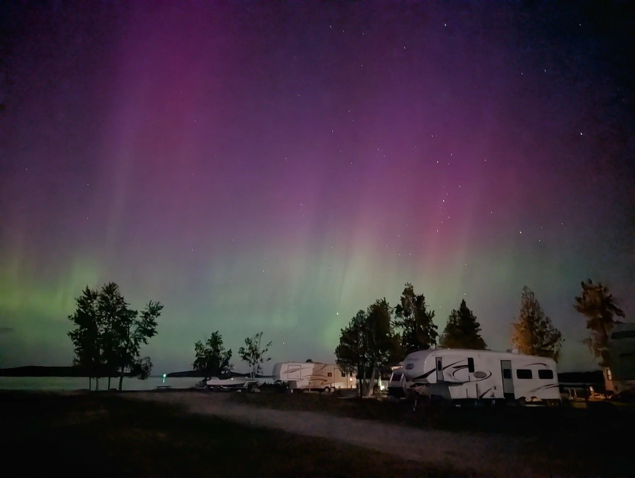  Vibrant purple and green Northern Lights dancing over the RVs and campsites at Drummond Island during the peak of the fall season in September.   