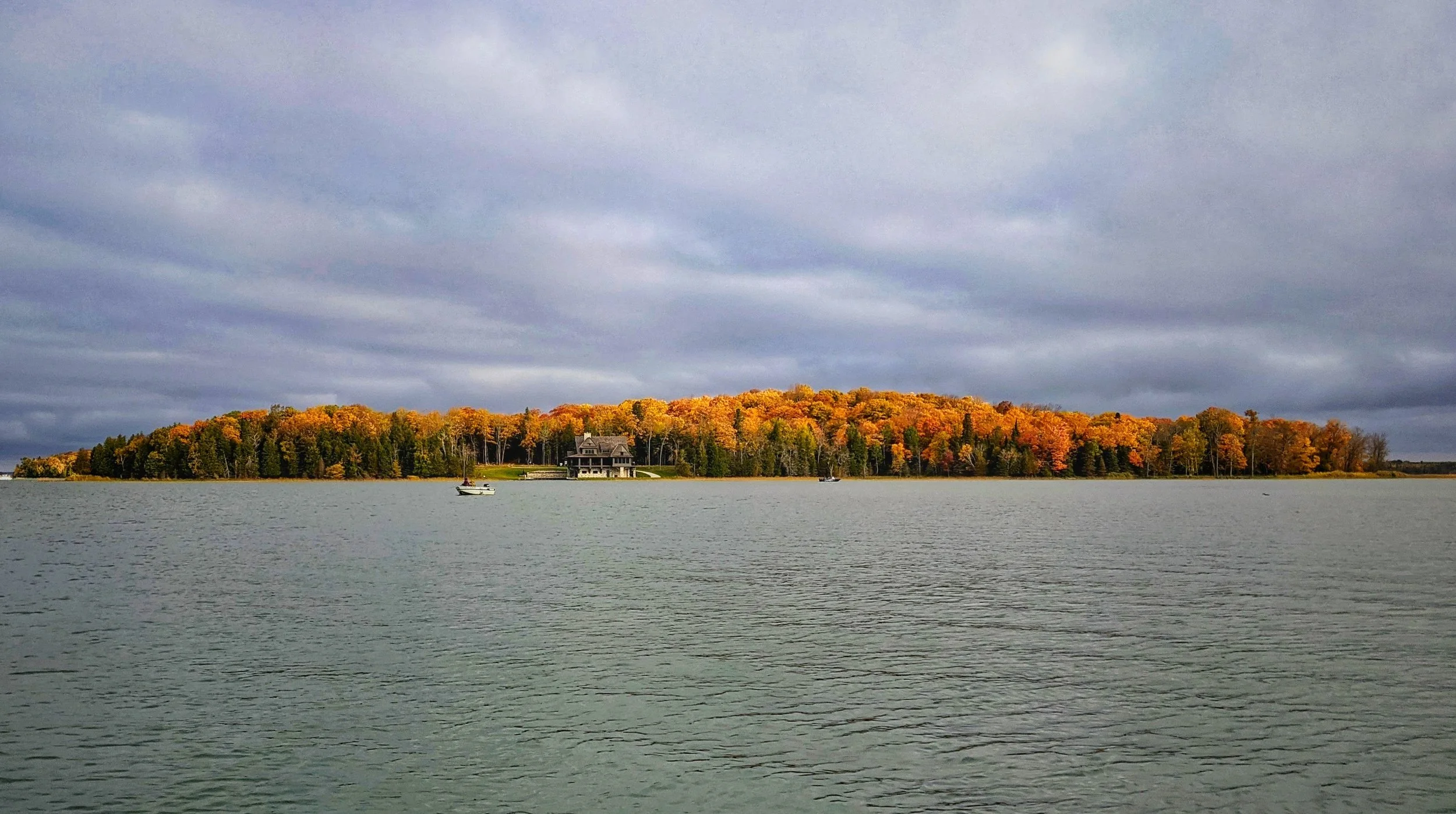  Stunning fall foliage and peak autumn colors along the rugged coastline of Drummond Island, seen from the water while heading out from Drummond Island Yacht Haven.   