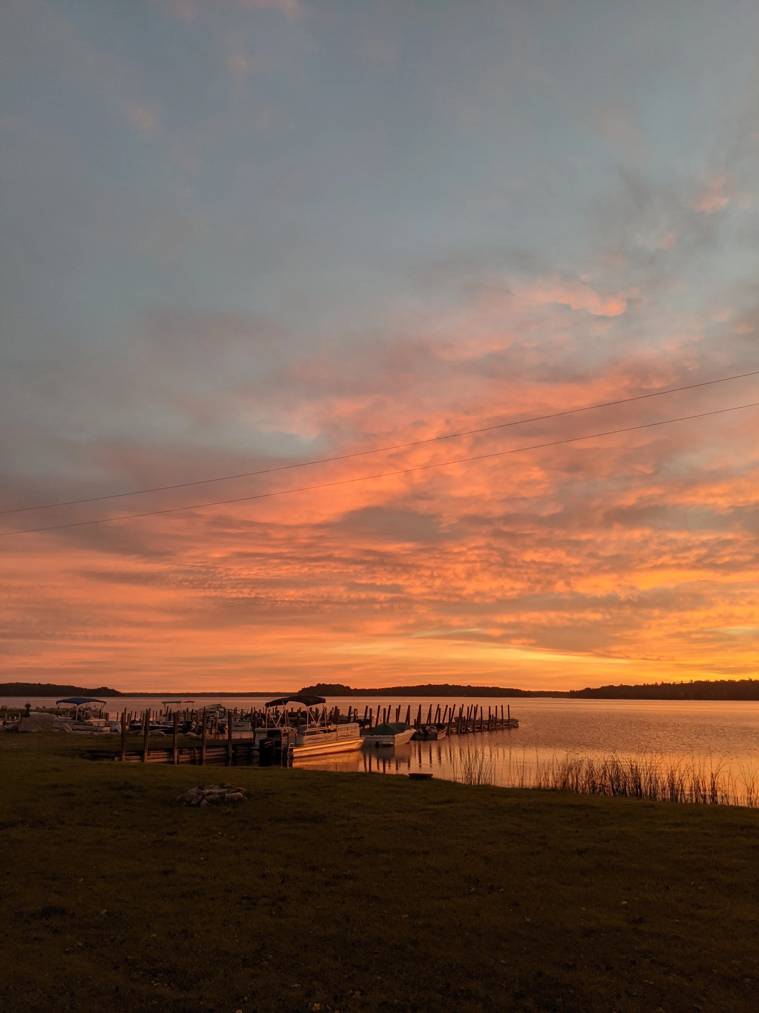  A vibrant sunset over the docks at Drummond Island Yacht Haven, highlighting the peaceful "Island Life" after a successful day of fall fishing. 