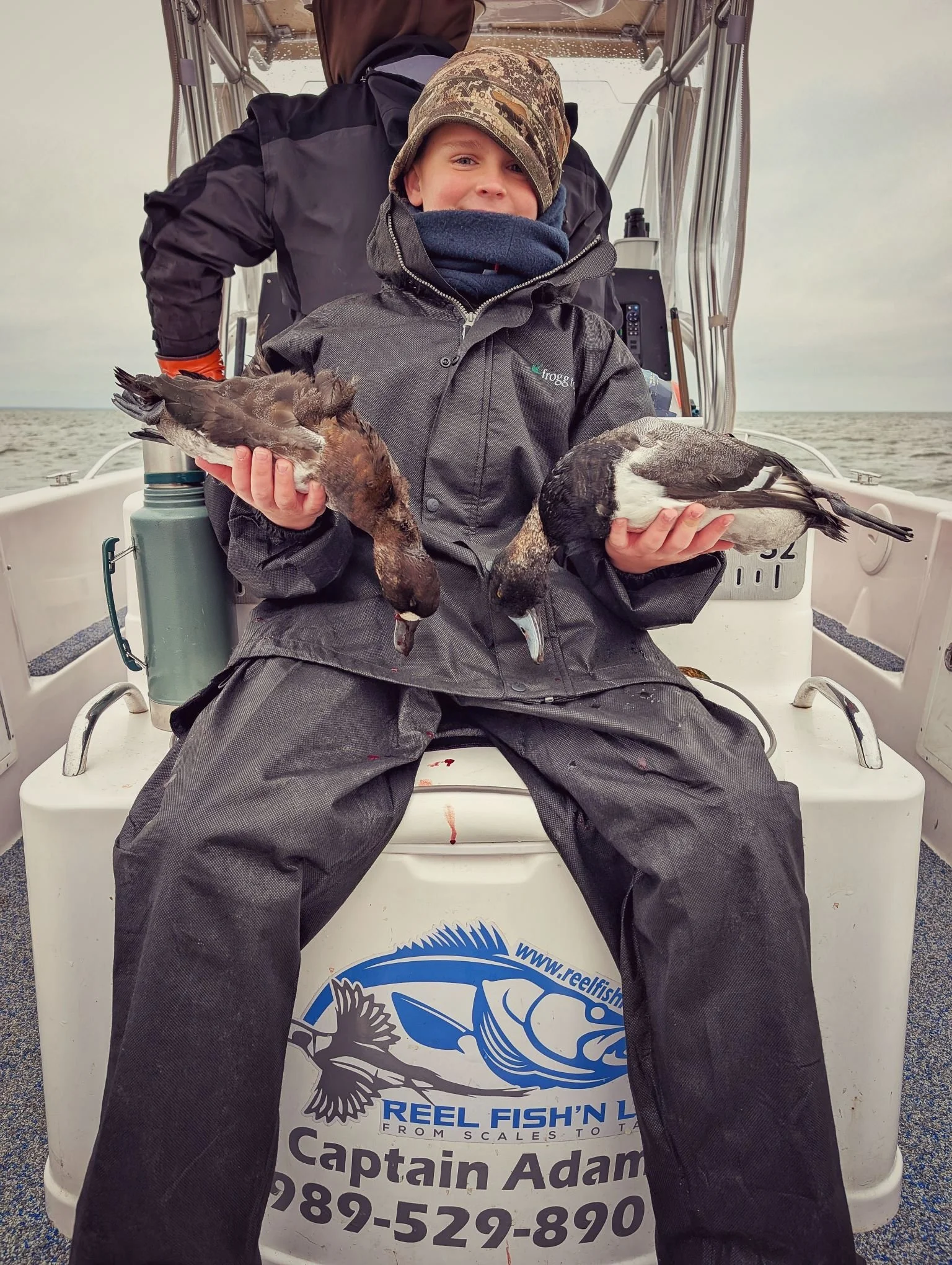  A young hunter proudly displaying a pair of ducks shot during a family-friendly Great Lakes waterfowl hunt with Reel Fish'n.   