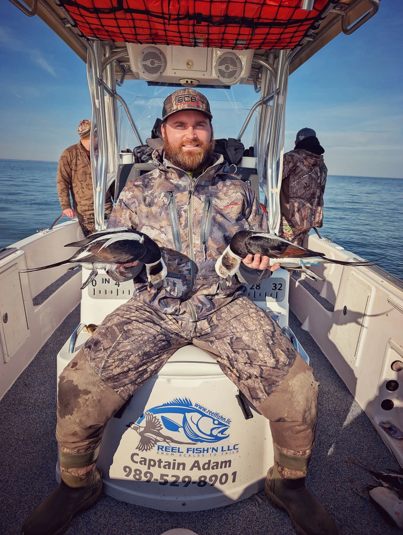  A successful sea duck hunter holding a pair of mature Longtails (Long-tailed ducks / Old Squaw) shot from a layout boat on Lake Huron with Reel Fish'n. 