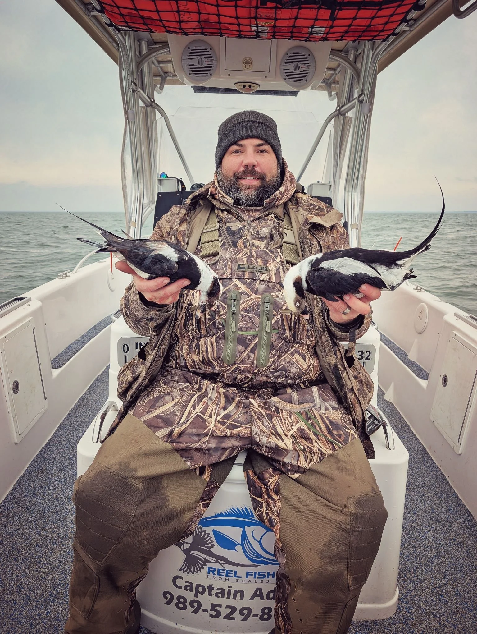  A successful waterfowler showcasing a pair of mature, trophy Longtails (Long-tailed ducks) shot during a guided Saginaw Bay sea duck hunt with Reel Fish'n.   