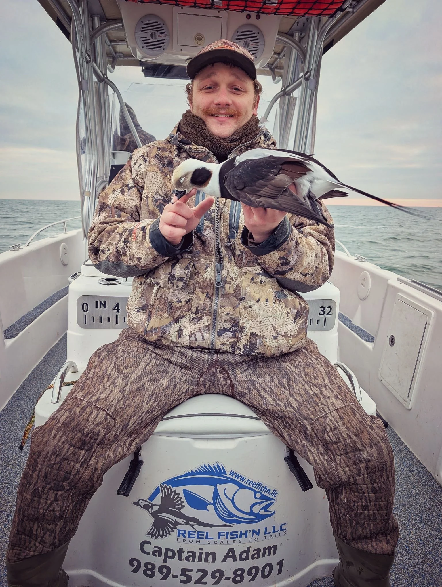  A successful sea duck hunter holding a trophy Longtail (Long-tailed duck / Old Squaw) shot during an open-water layout boat hunt on Lake Huron with Reel Fish'n. 