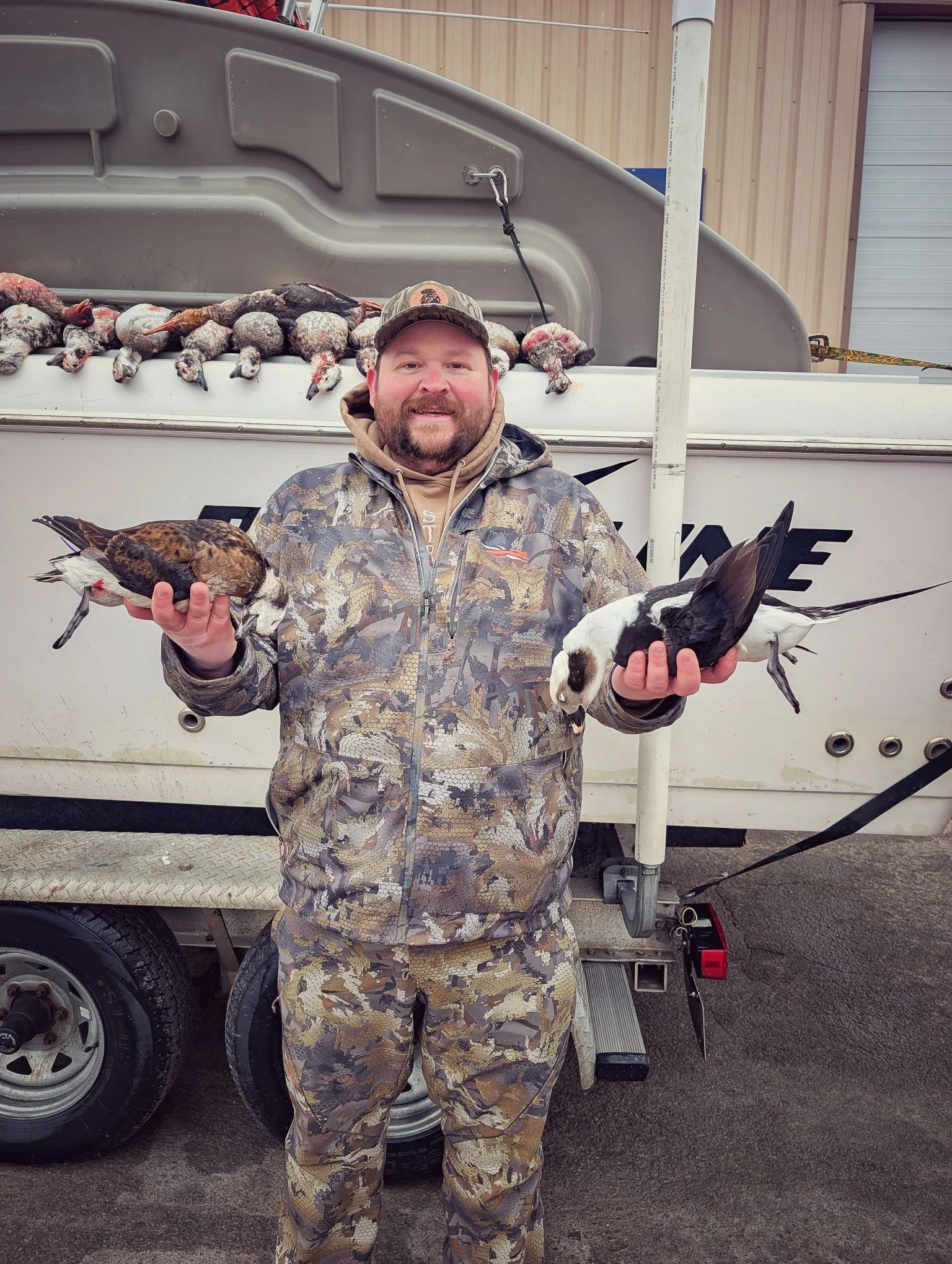  A successful hunter holding a prime Longtail (Old Squaw) and a diver duck harvested during a specialized open-water layout boat hunt with Reel Fish'n.   