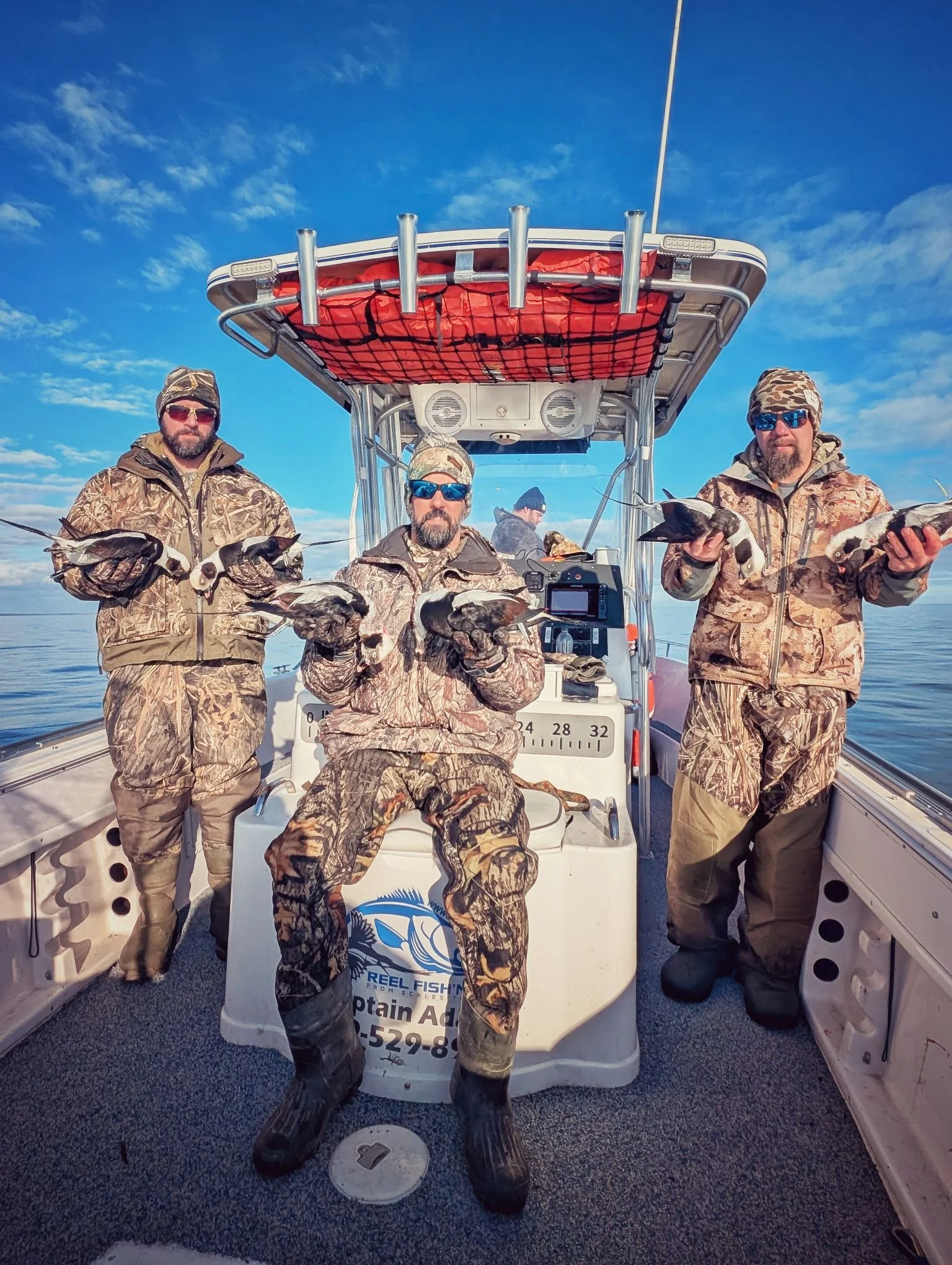  A group of hunters celebrating a successful morning on the Great Lakes, displaying a mixed bag of sea ducks harvested from layout boats.   