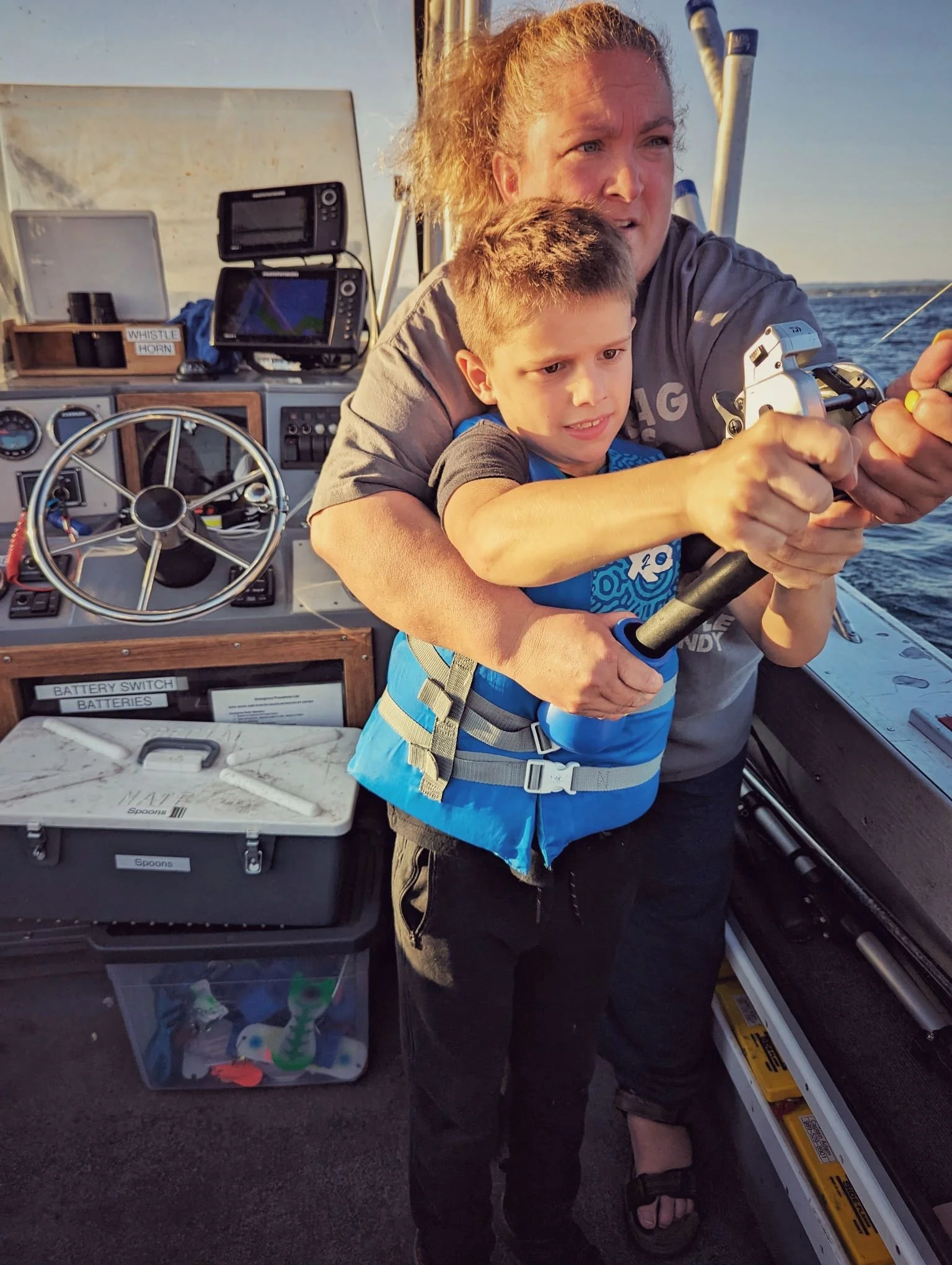  A young angler getting some help reeling in a big one on the Proline during a family-friendly salmon and trout fishing trip on Grand Traverse Bay.   