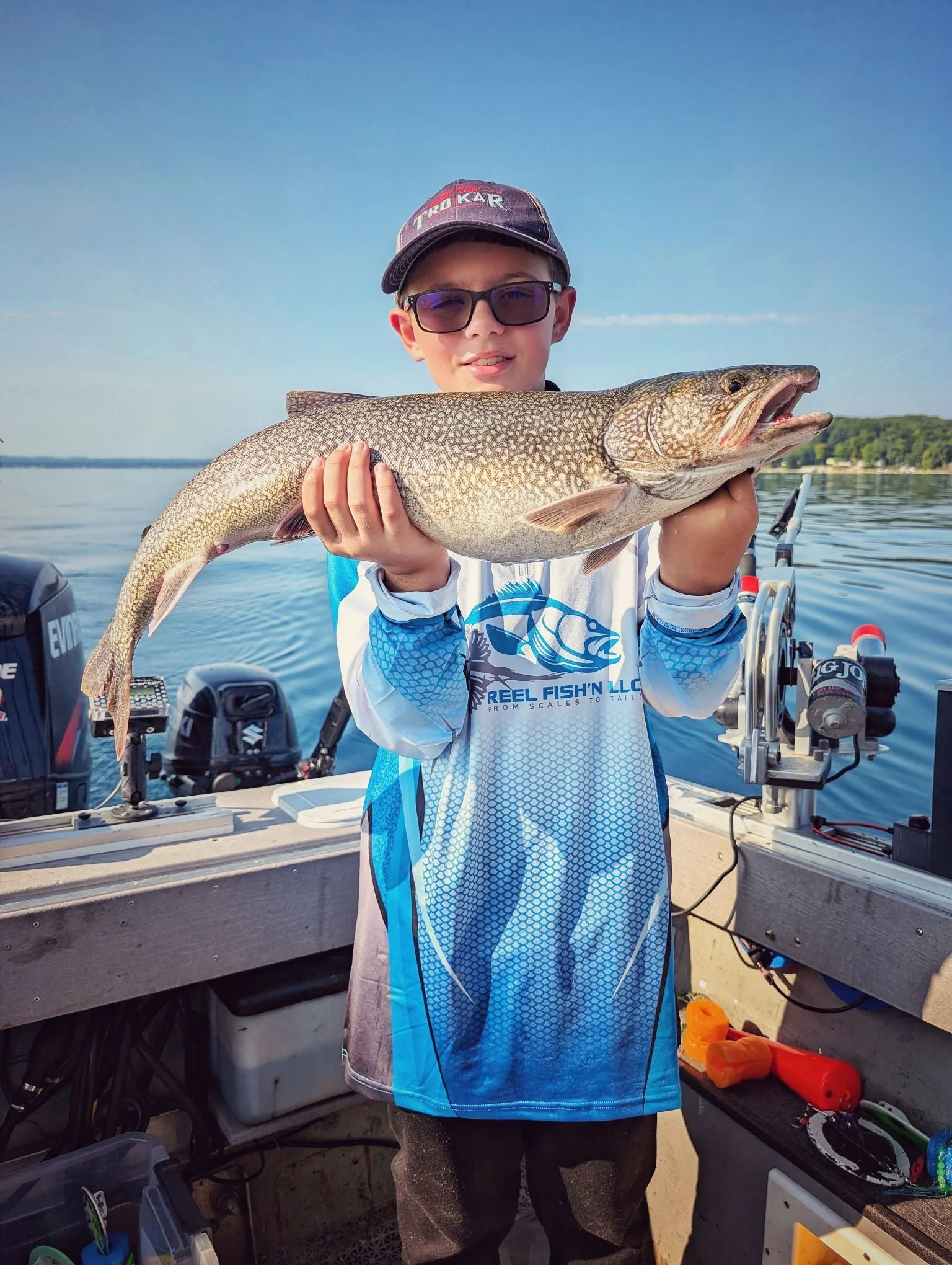  A young fisherman proudly holding a fresh Lake Trout caught during a family-friendly charter on Grand Traverse Bay.   