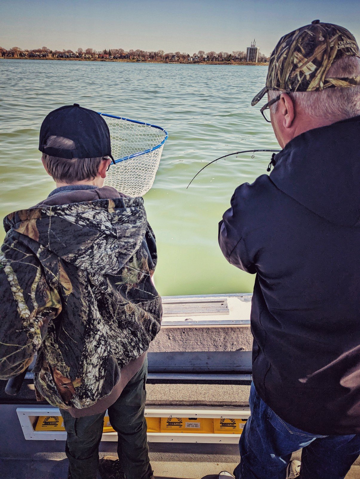  A young boy in camouflage watching closely as a Reel Fish'n guide nets a fish on the Detroit River during a spring walleye charter. 