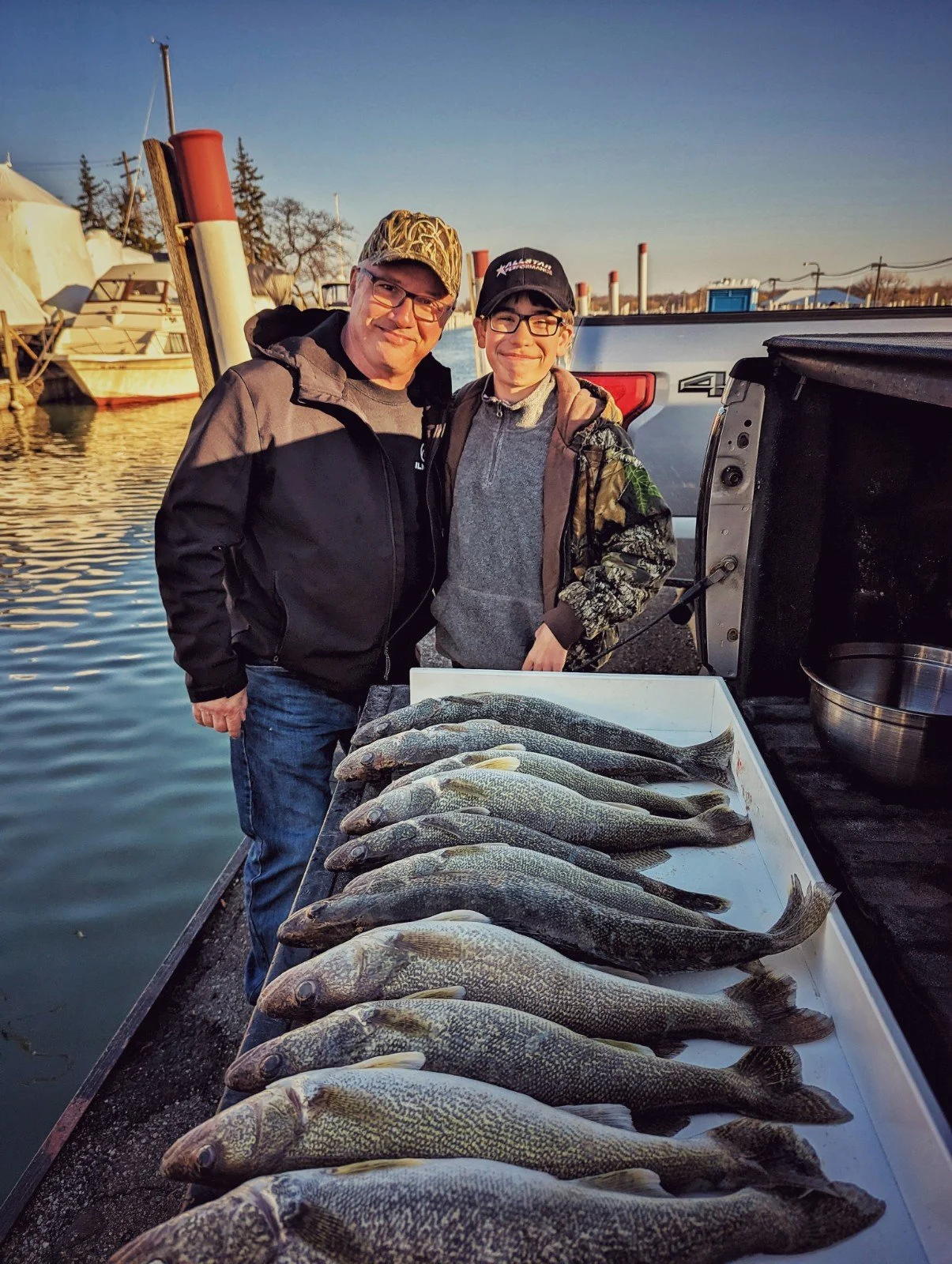  A father and son standing behind a table full of limit-caught Detroit River walleye after a morning charter with Reel Fish'n. 