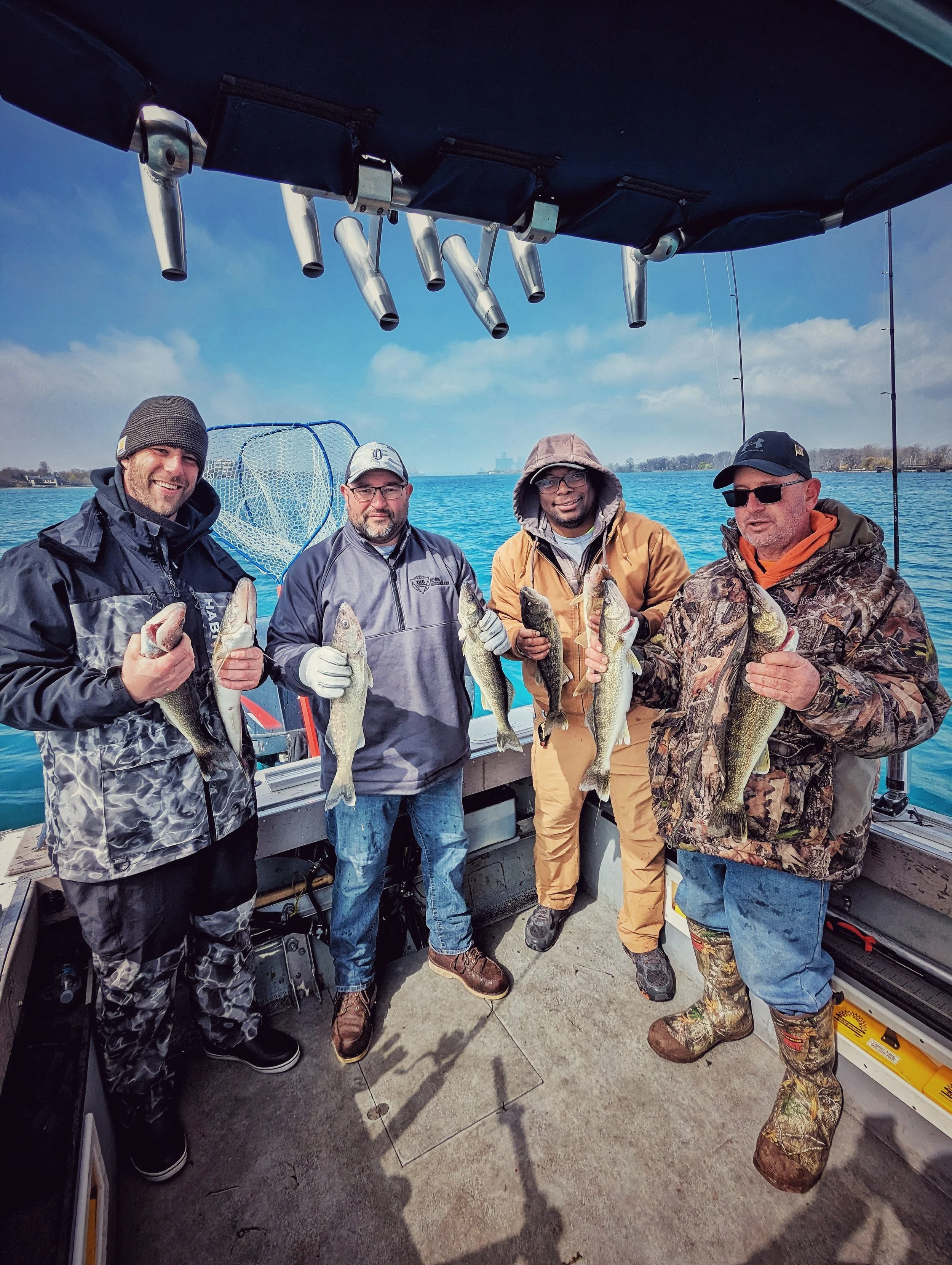 A group of four anglers in cold-weather gear holding up fresh walleye on a Reel Fish'n charter boat during the early spring Detroit River run. 