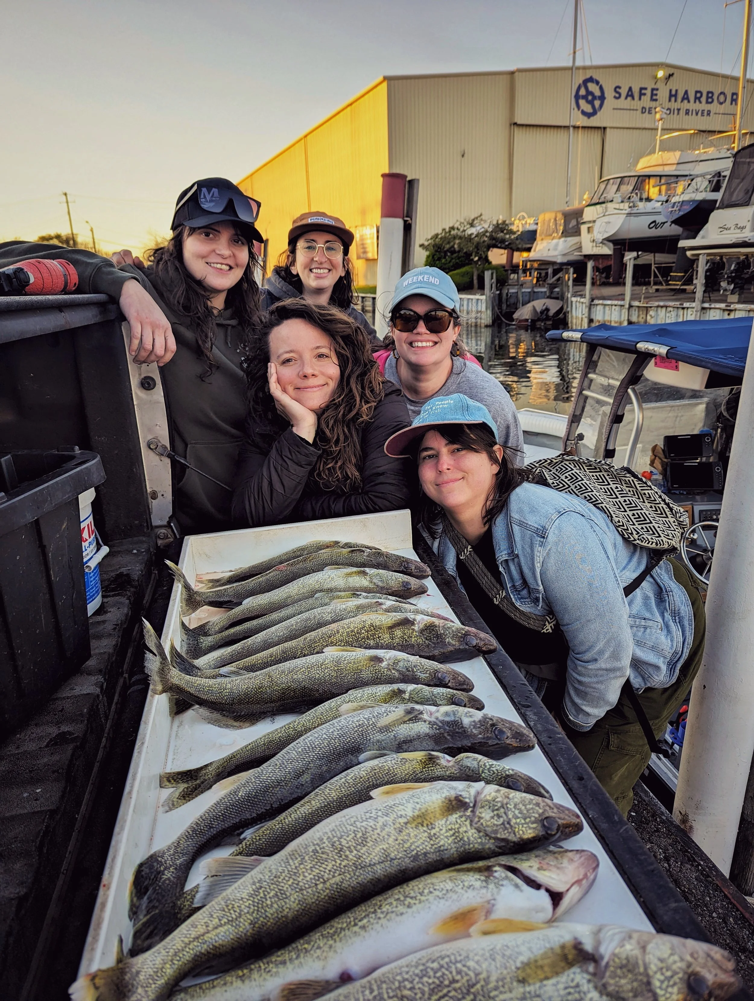  A group of five women posing with their full limit of Detroit River walleye on a cleaning table after a successful Reel Fish'n charter. 