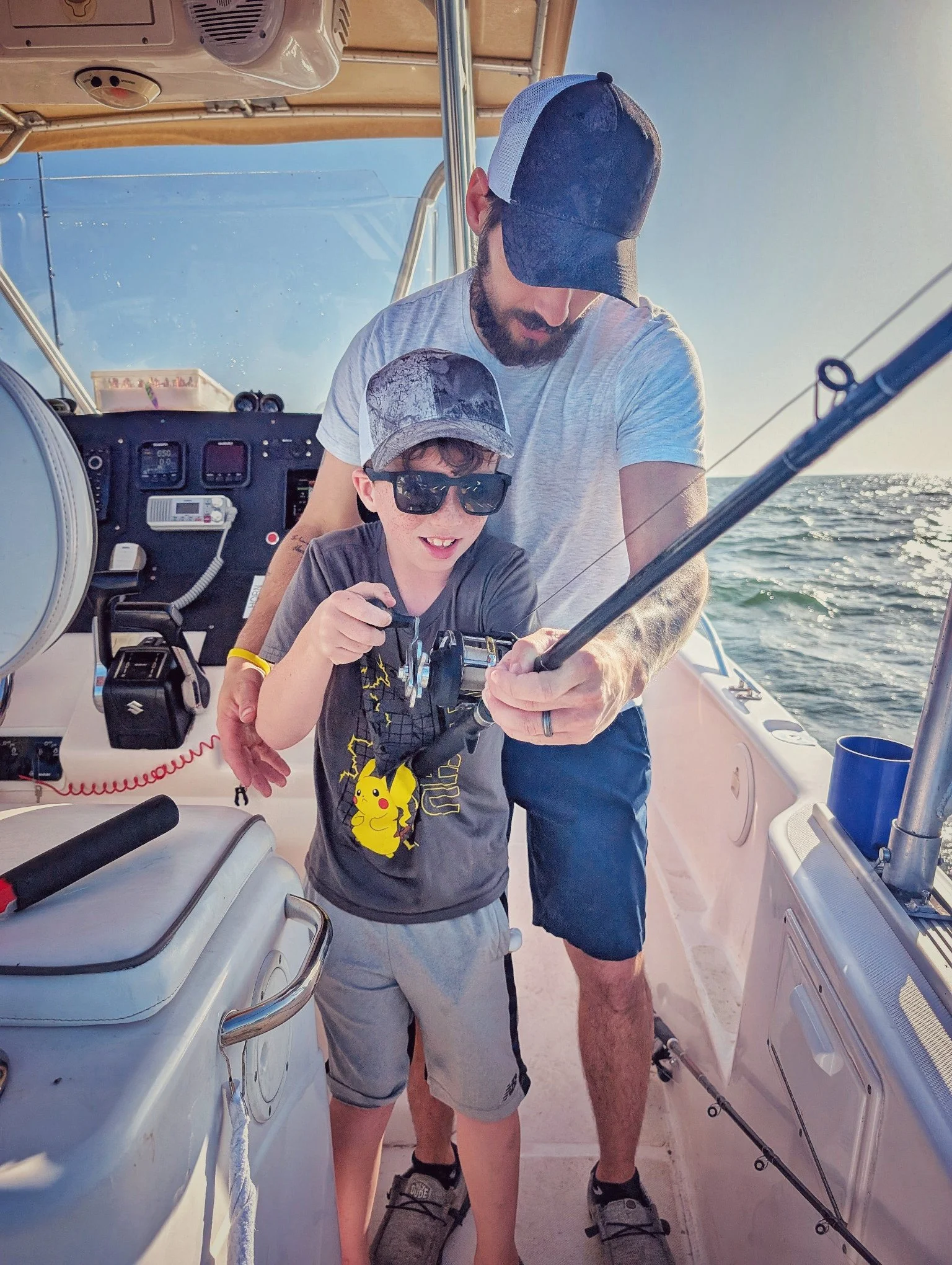  A father helping his young son reel in a fish during a family-friendly walleye charter on Saginaw Bay with Reel Fish'n LLC. 