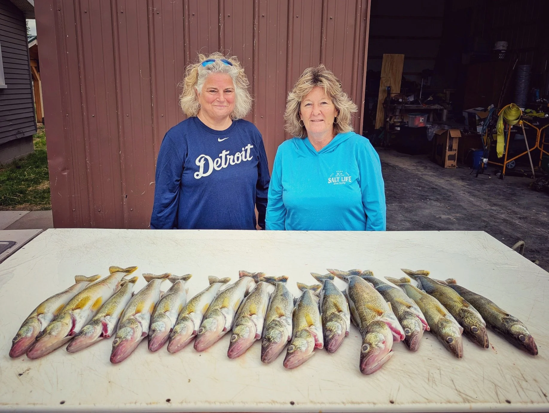  Two female anglers smiling behind a full limit of Saginaw Bay walleye on a cleaning table after a successful morning fishing charter with Reel Fish'n LLC out of Linwood, MI. 