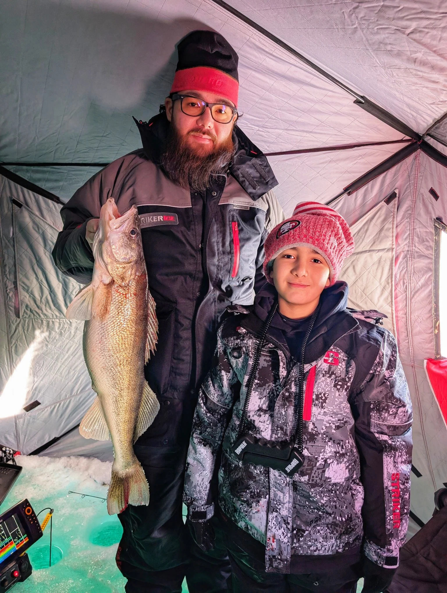  Anglers posing with a Saginaw Bay walleye inside a heated ice fishing shanty during a winter guide trip out of Linwood, MI, with Reel Fish'n LLC.   