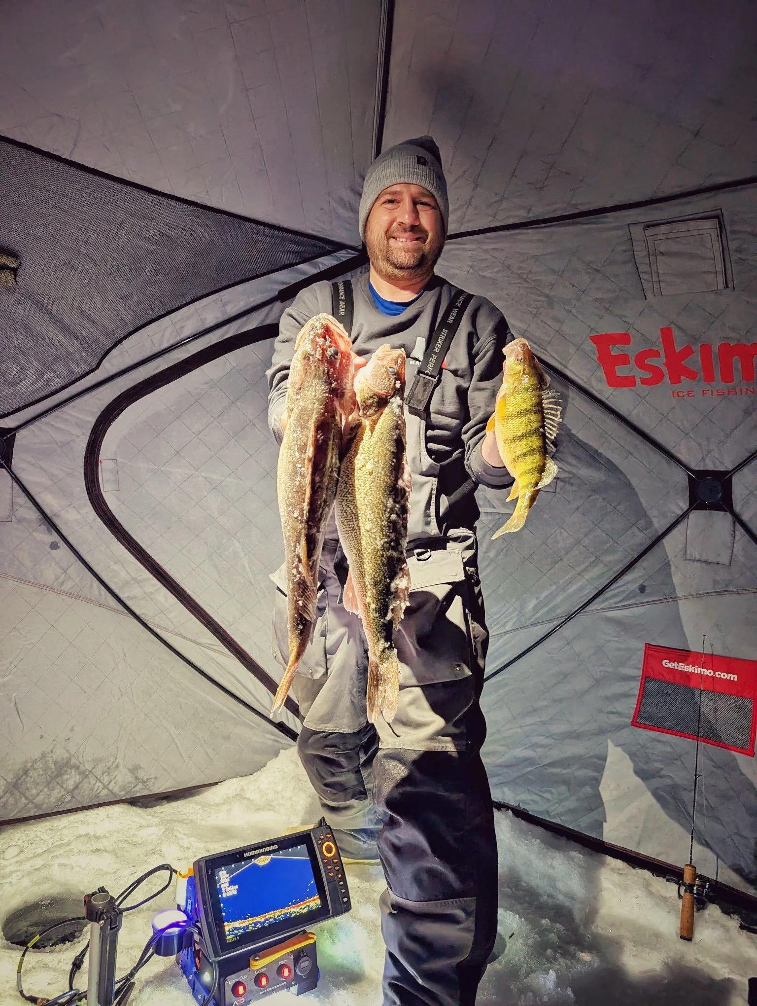  A successful ice fisherman showcasing a limit of Saginaw Bay walleye while using high-end sonar electronics on a Reel Fish'n LLC ice fishing charter.   