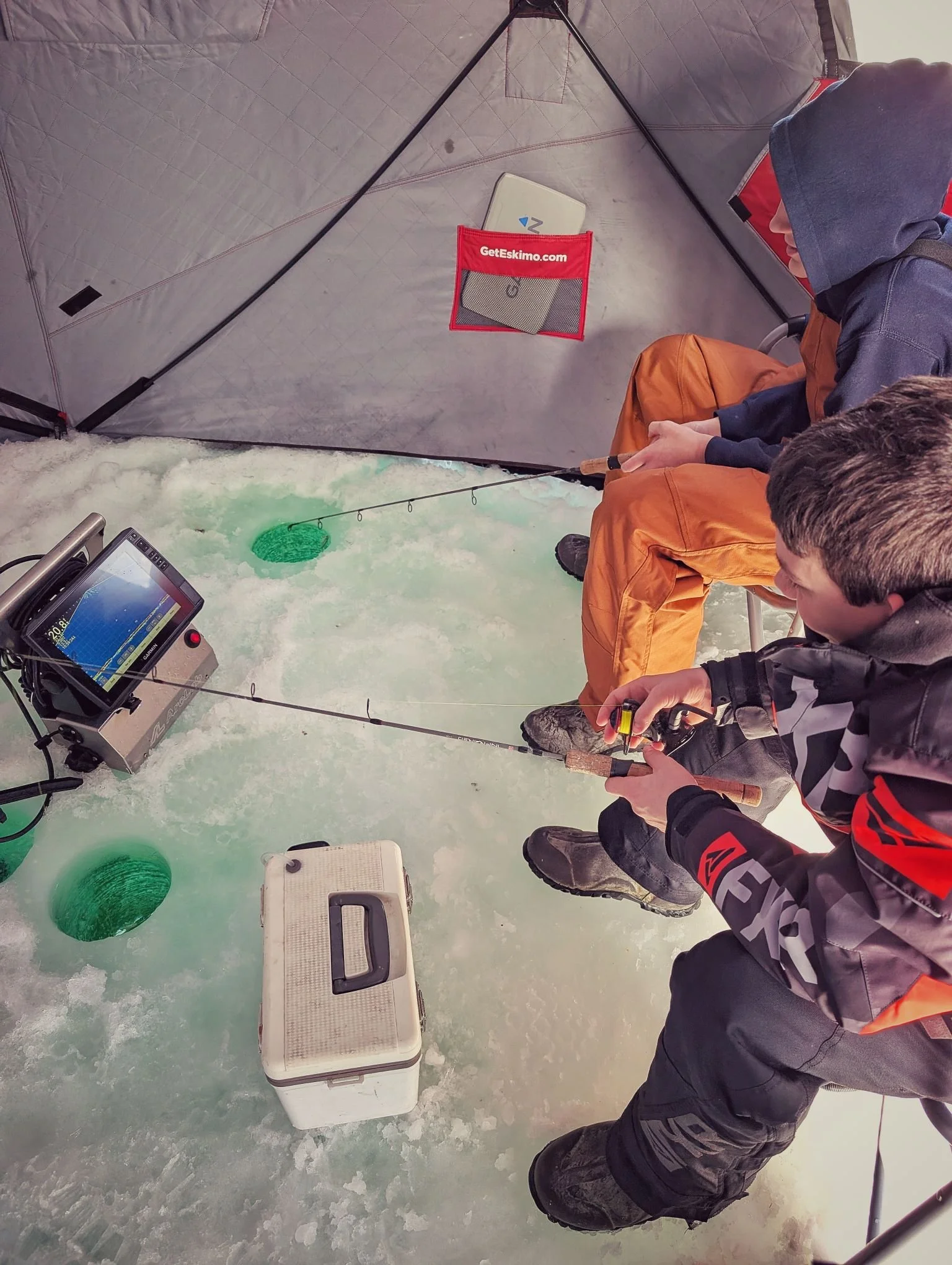  Anglers using live-scanning sonar to track walleye through the ice during a guided Saginaw Bay ice fishing charter with Reel Fish'n LLC.   