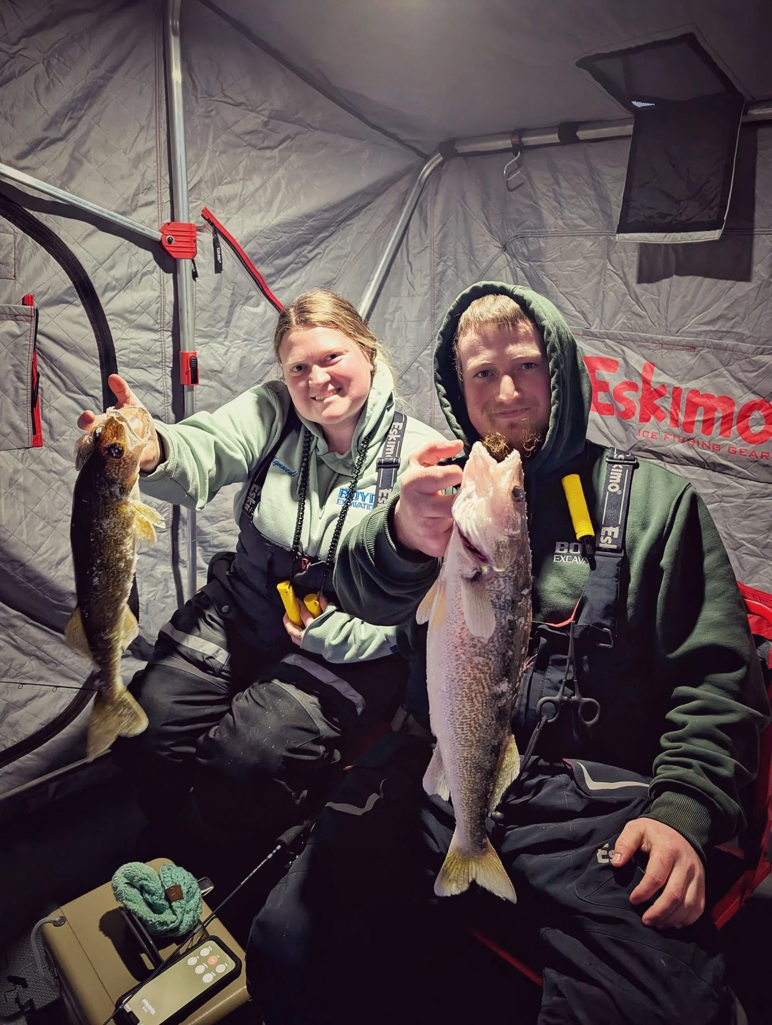  Two successful young anglers holding up a double header of walleye inside a portable ice fishing shanty on Saginaw Bay with Reel Fish'n LLC.   