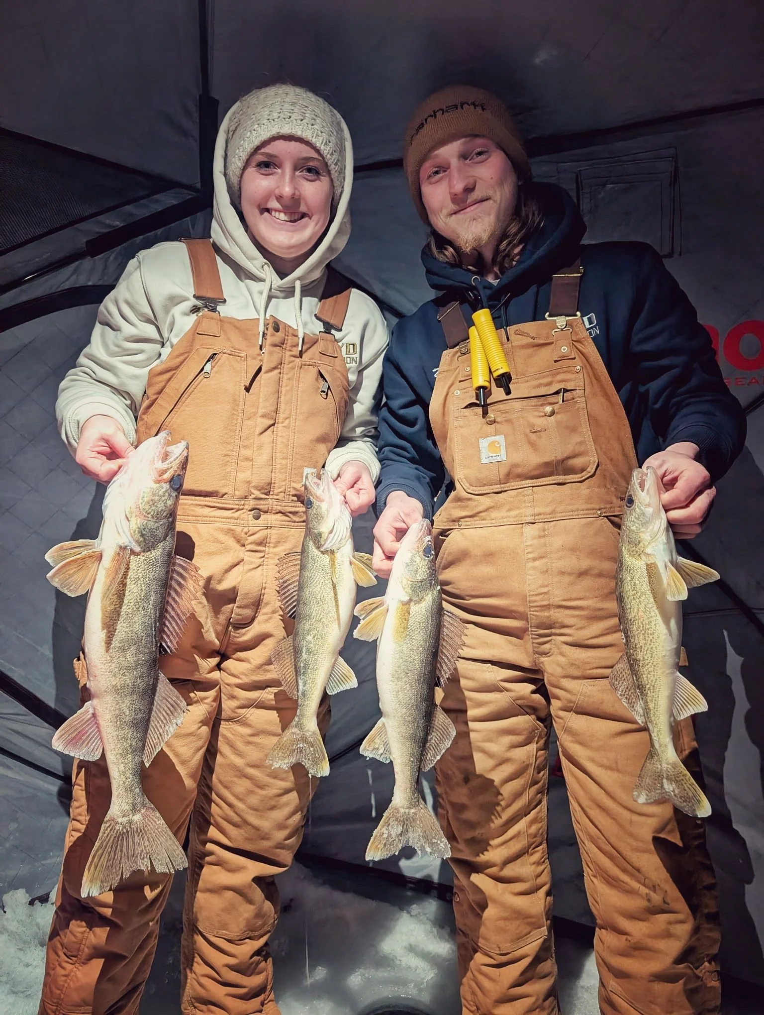  A happy couple showcasing a limit of Saginaw Bay walleye caught during a guided evening ice fishing trip with Reel Fish'n.   